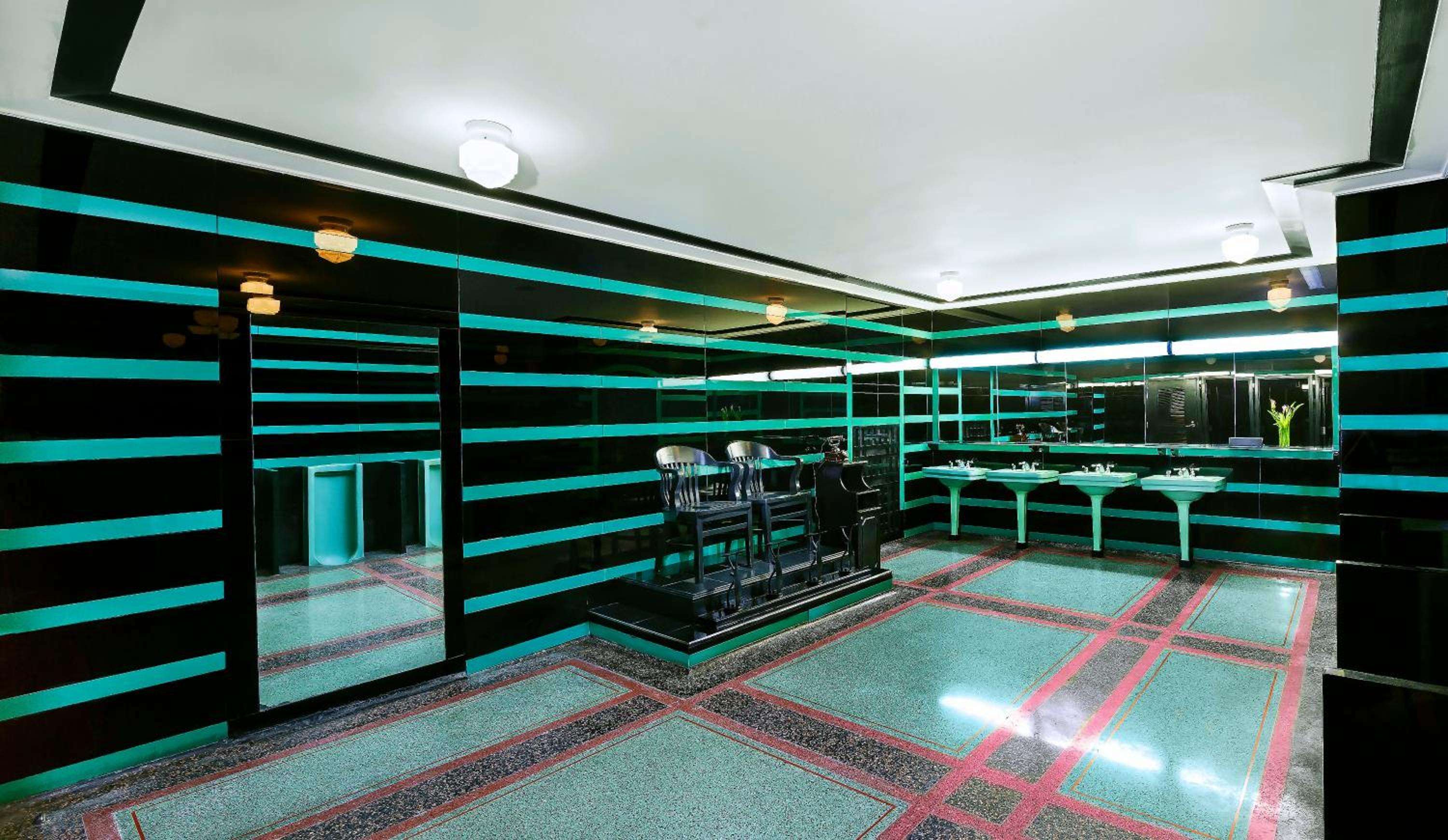 Neon-striped walls and geometric terrazzo floors create a retro-futuristic fitness sanctuary where vintage exercise equipment meets bold 1980s design aesthetics.