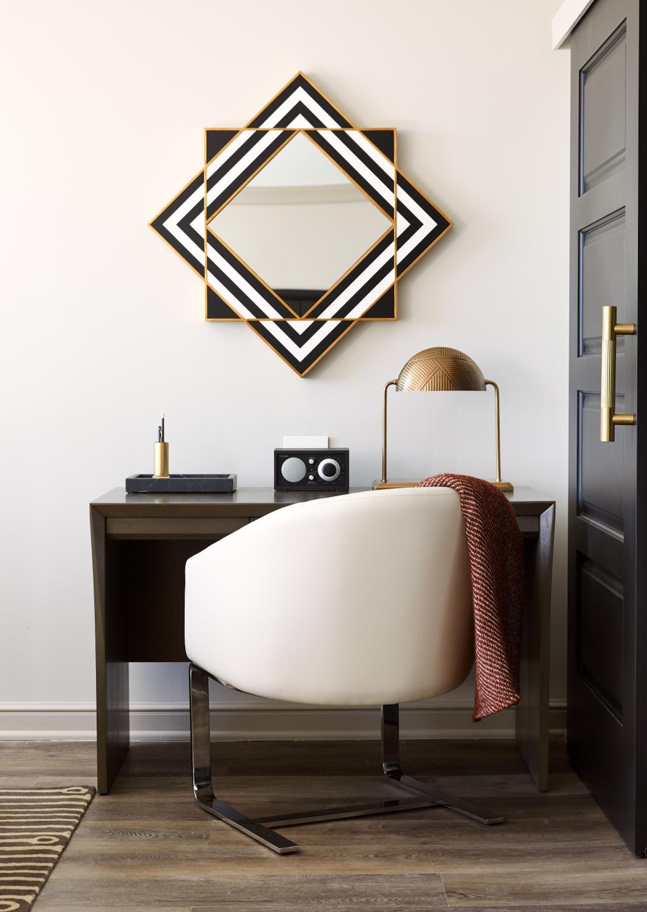 Geometric mirrors and brass accents create sophisticated drama in this thoughtfully appointed workspace, where modern comfort meets timeless design elements.