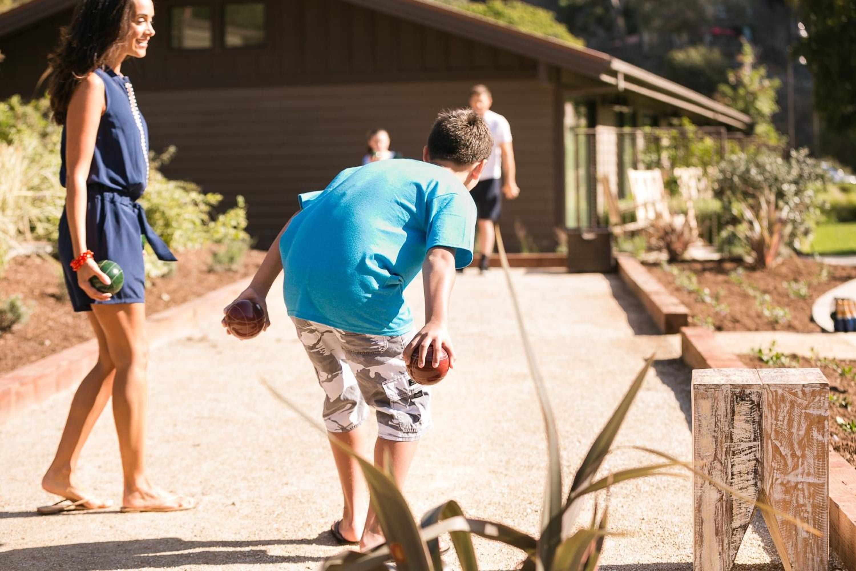 Sun-drenched bocce courts invite friendly competition among guests, with weathered wooden planters and native plantings creating an authentic California ranch atmosphere.