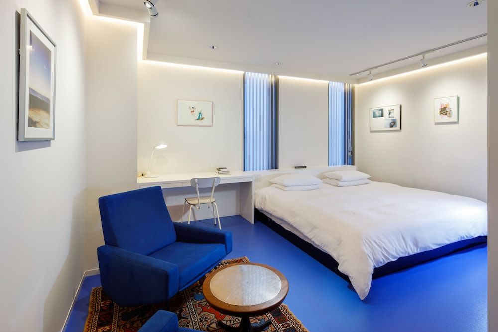 Crisp white linens contrast beautifully against the bold cobalt flooring, while warm LED strips create an intimate cocoon in this thoughtfully designed guest room.