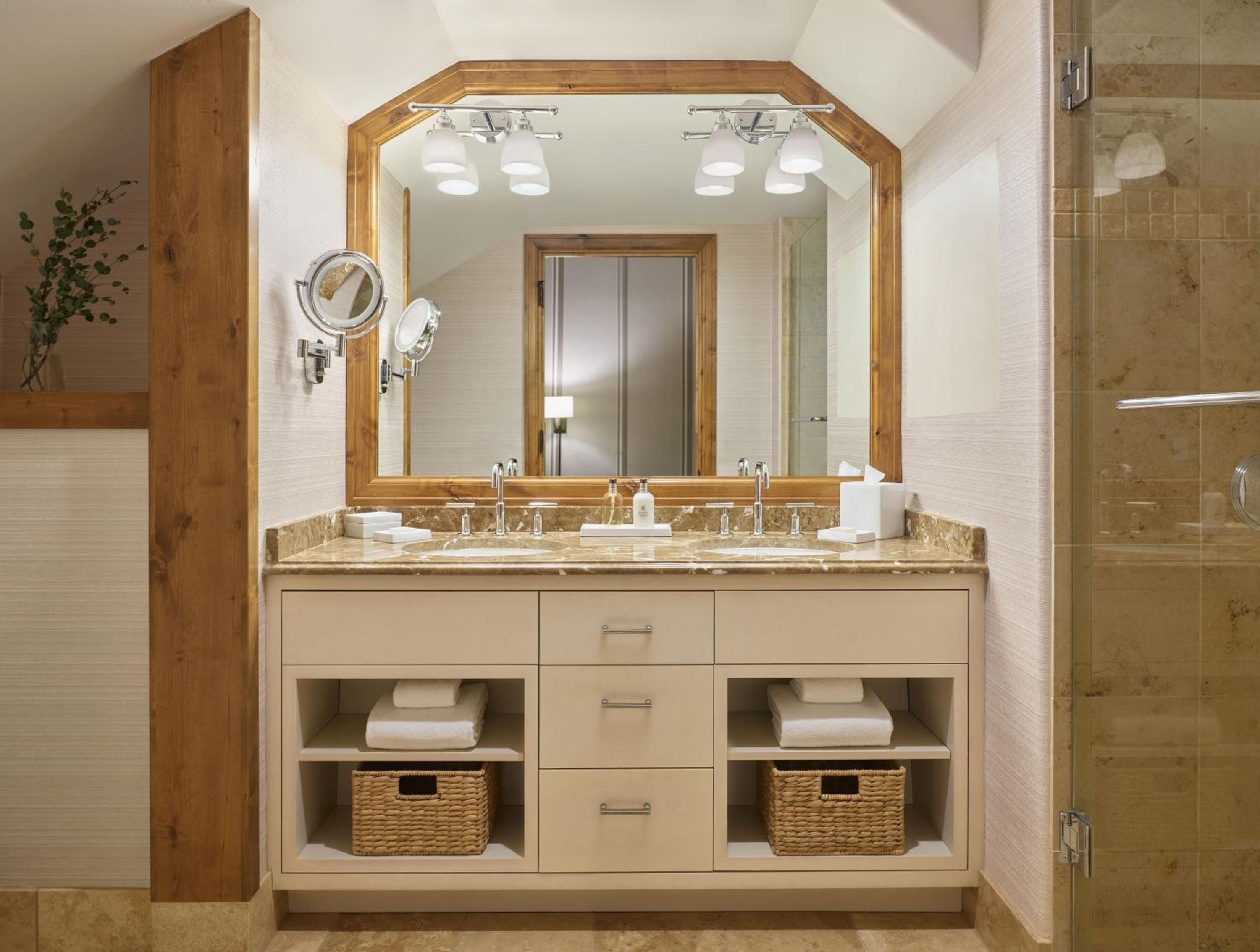Warm wood tones and marble surfaces create a spa-like sanctuary, where thoughtful details like woven baskets and dual vanities elevate the mountain lodge experience.