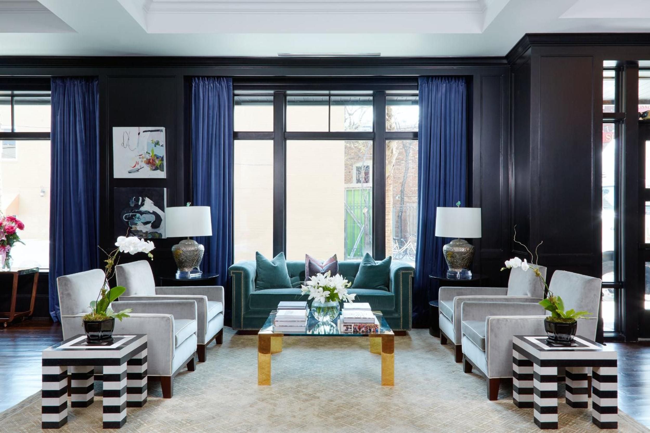 Sophisticated navy walls and rich jewel tones create an intimate gathering space where brass accents catch afternoon light streaming through tall windows.