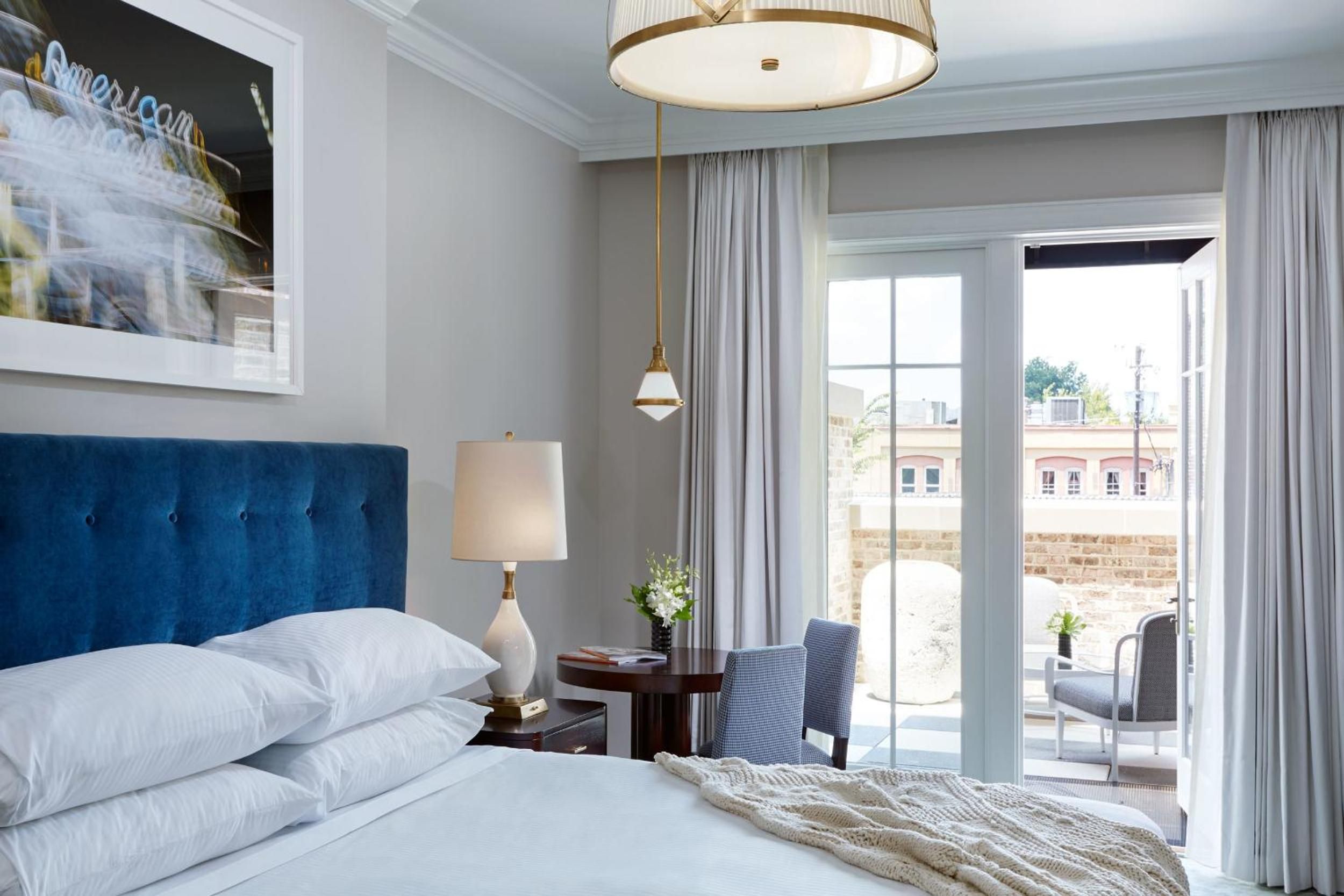 Crisp white linens contrast beautifully with the navy velvet headboard, while French doors open to a private balcony overlooking Charleston's historic rooftops.