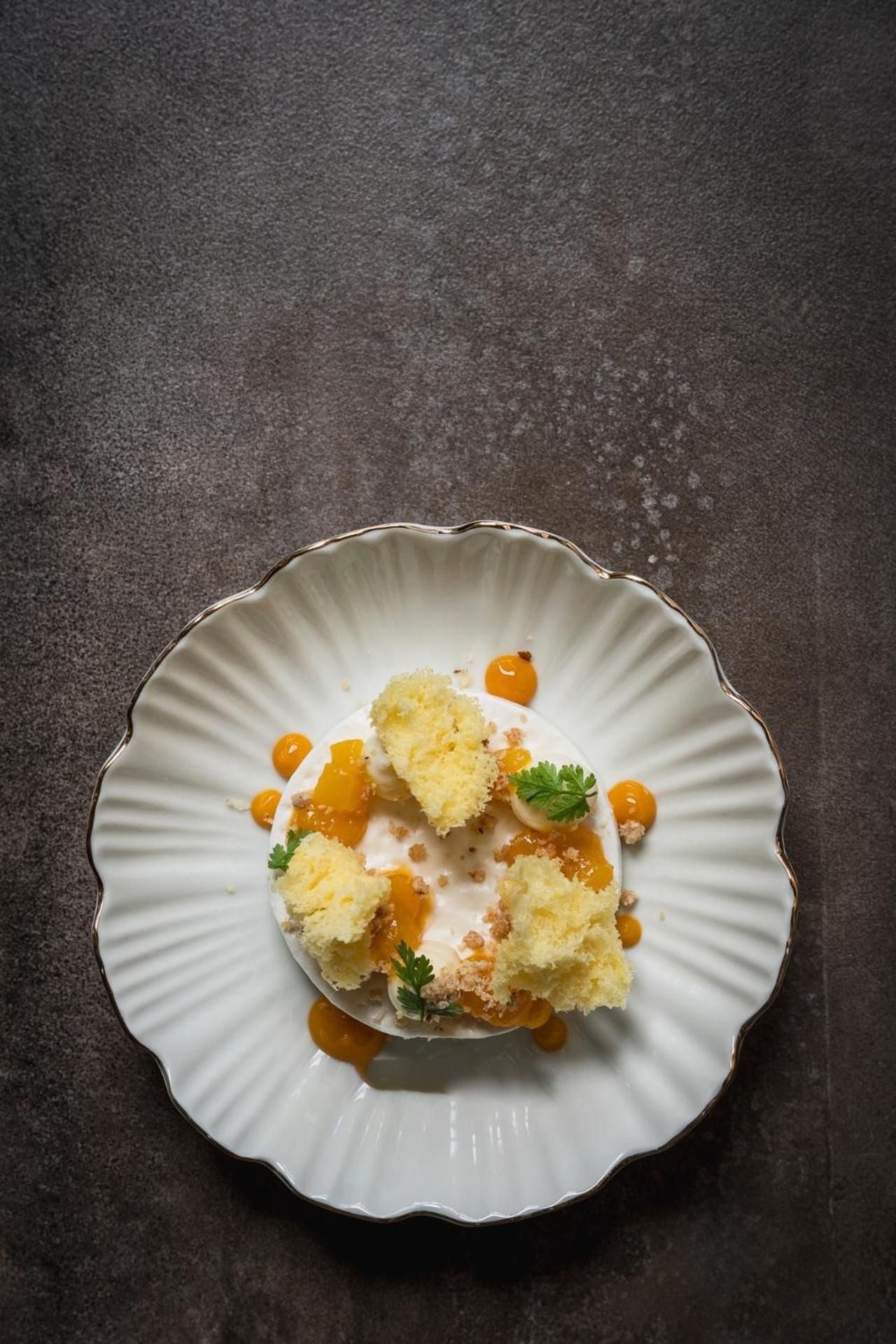 Delicate quenelles of house-made gelato nestle alongside golden sea buckthorn pearls on vintage porcelain, showcasing the kitchen's artful precision and seasonal Swiss ingredients.