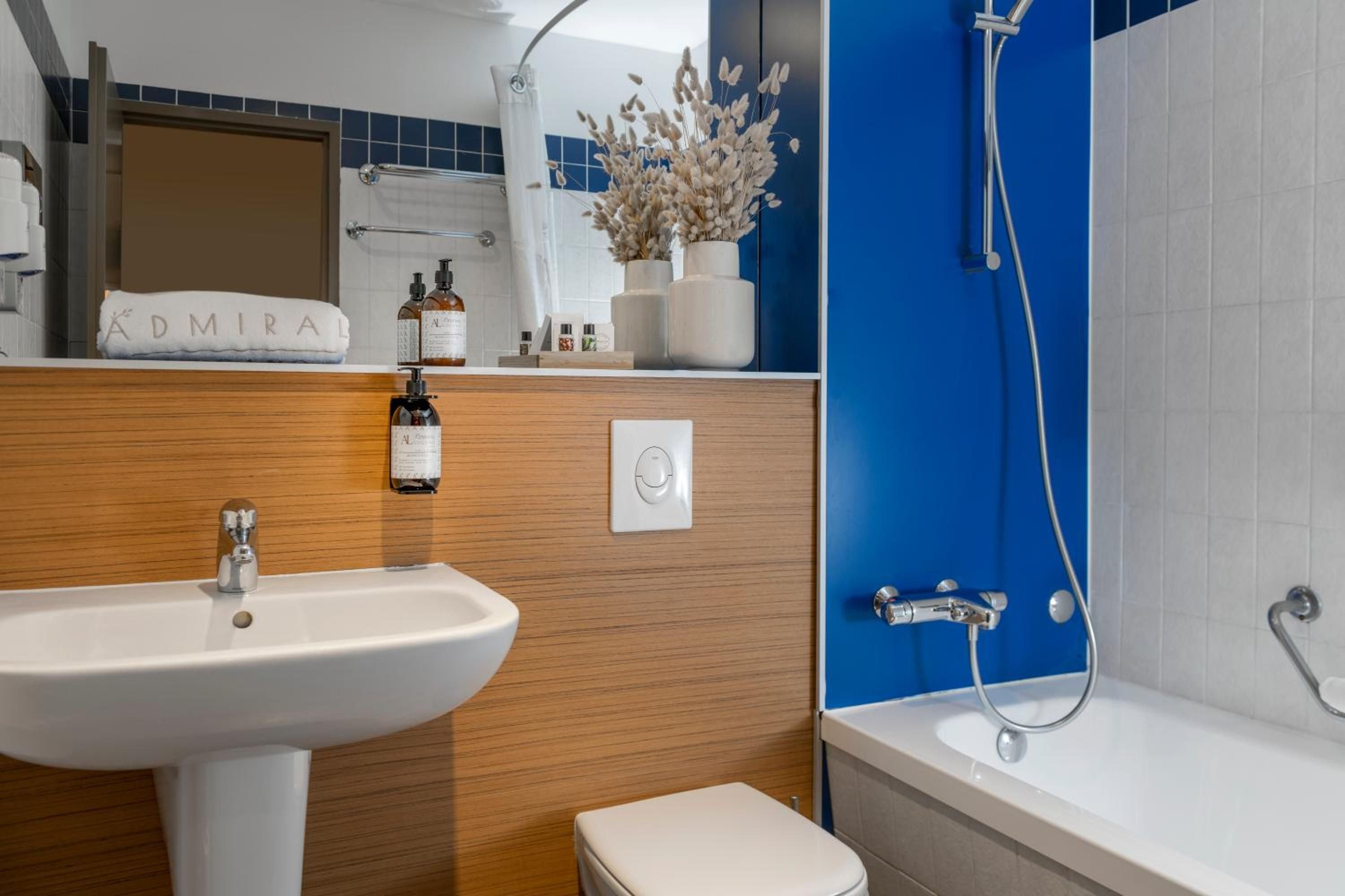 Wood-paneled walls and cobalt blue accents create a yacht-like intimacy in this cleverly designed bathroom, where every surface serves both function and style.