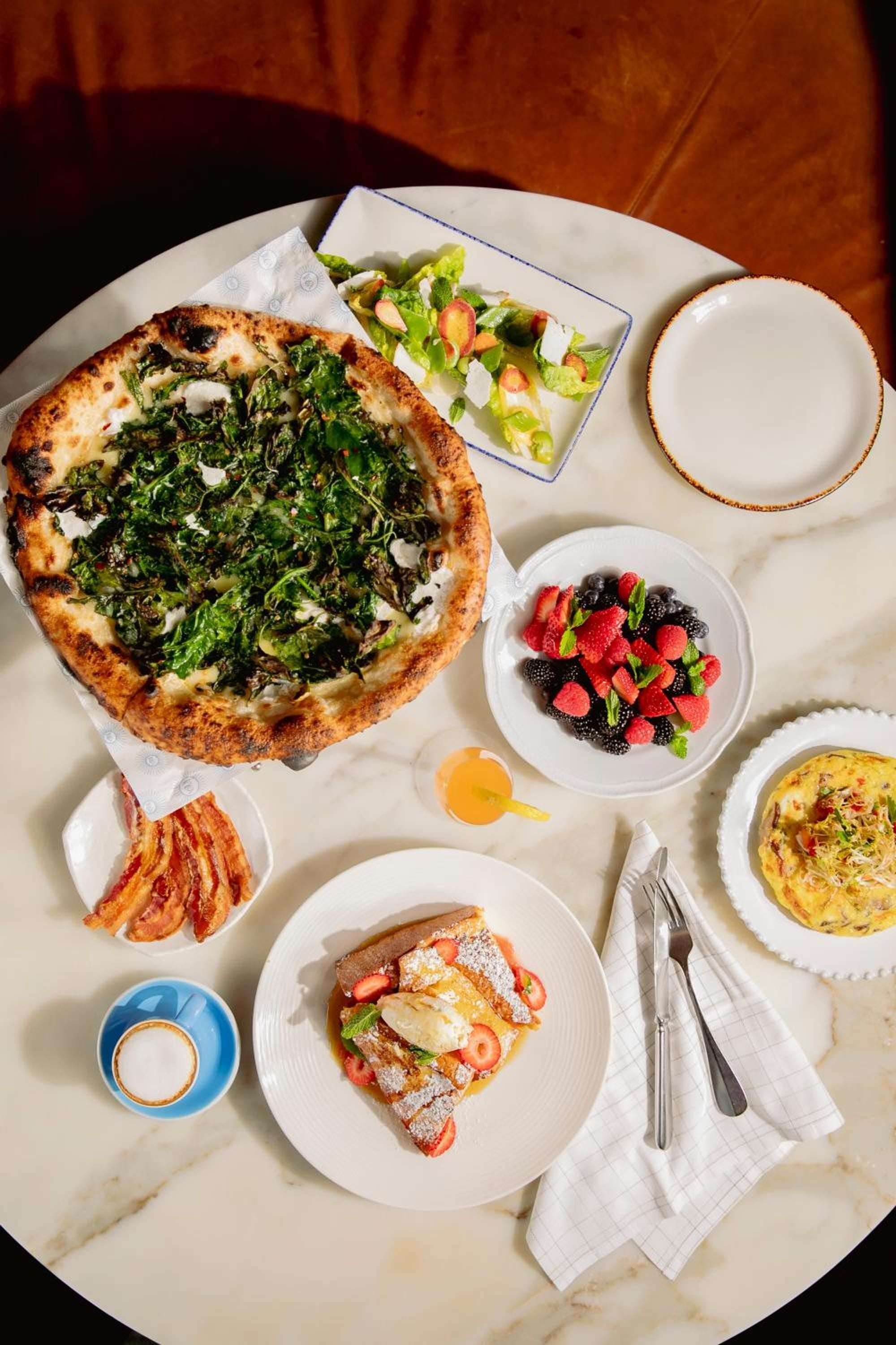 Golden morning light illuminates a lavish brunch spread featuring house-made quiche, fresh berries, and artisanal coffee served on elegant white porcelain at this Brooklyn culinary destination.