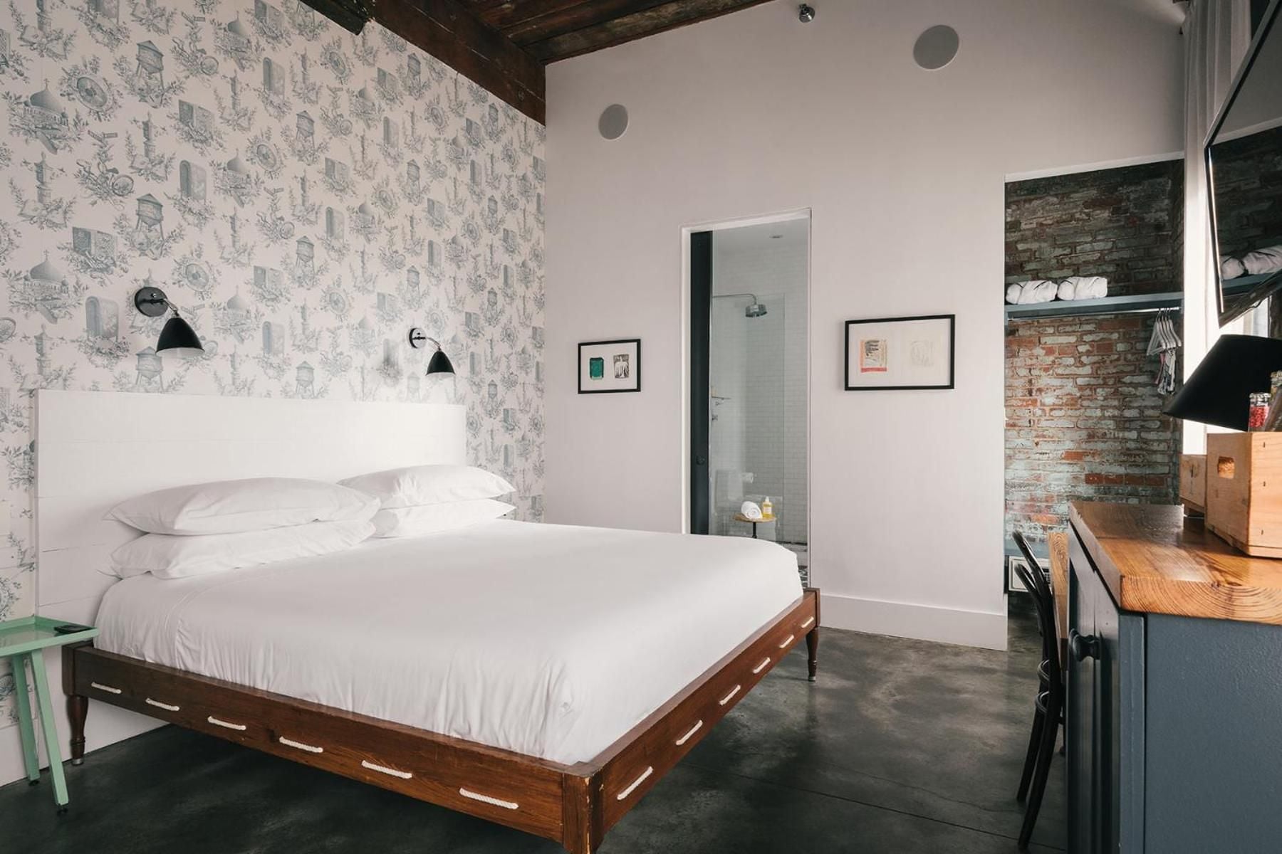Exposed brick meets whimsical wallpaper in this thoughtfully curated room, where industrial concrete floors ground playful design touches and black sconce lighting creates intimate ambiance.