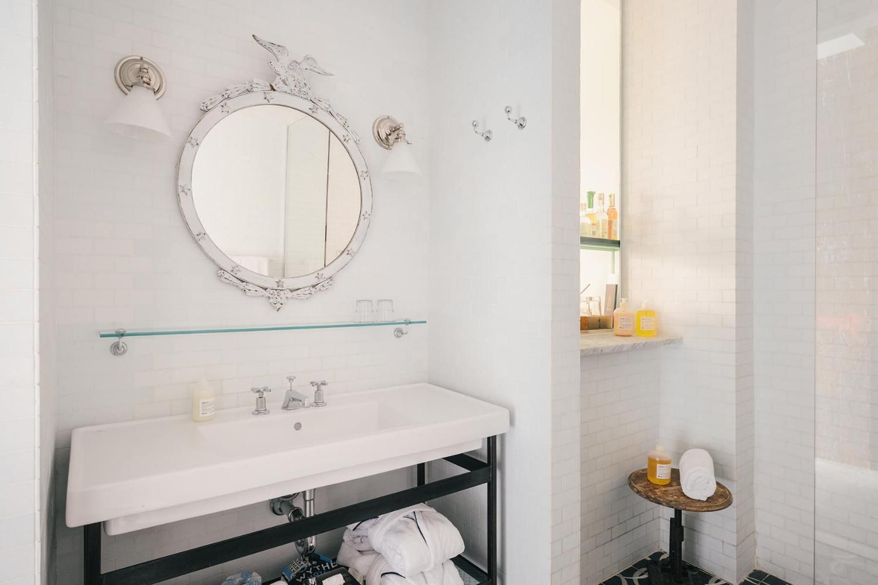 Ornate vintage mirror and sleek marble vanity create an elegant contrast in this thoughtfully designed bathroom, where brass fixtures catch soft natural light.