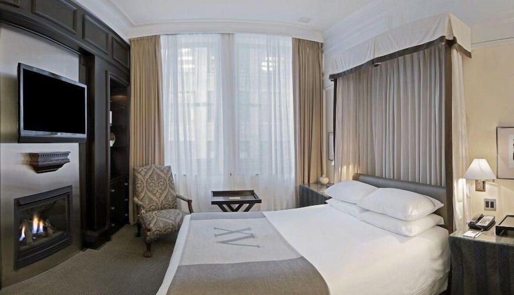 Crisp white linens and flickering firelight create an intimate sanctuary, where dark wood millwork frames panoramic city views through silk-draped windows.