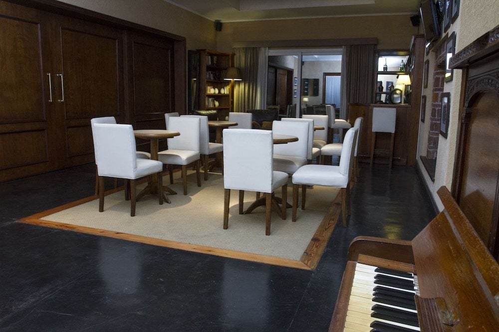 Warm wood tones and crisp white dining chairs create an inviting gathering space, while a vintage piano adds authentic Argentine estancia charm to the communal dining area.