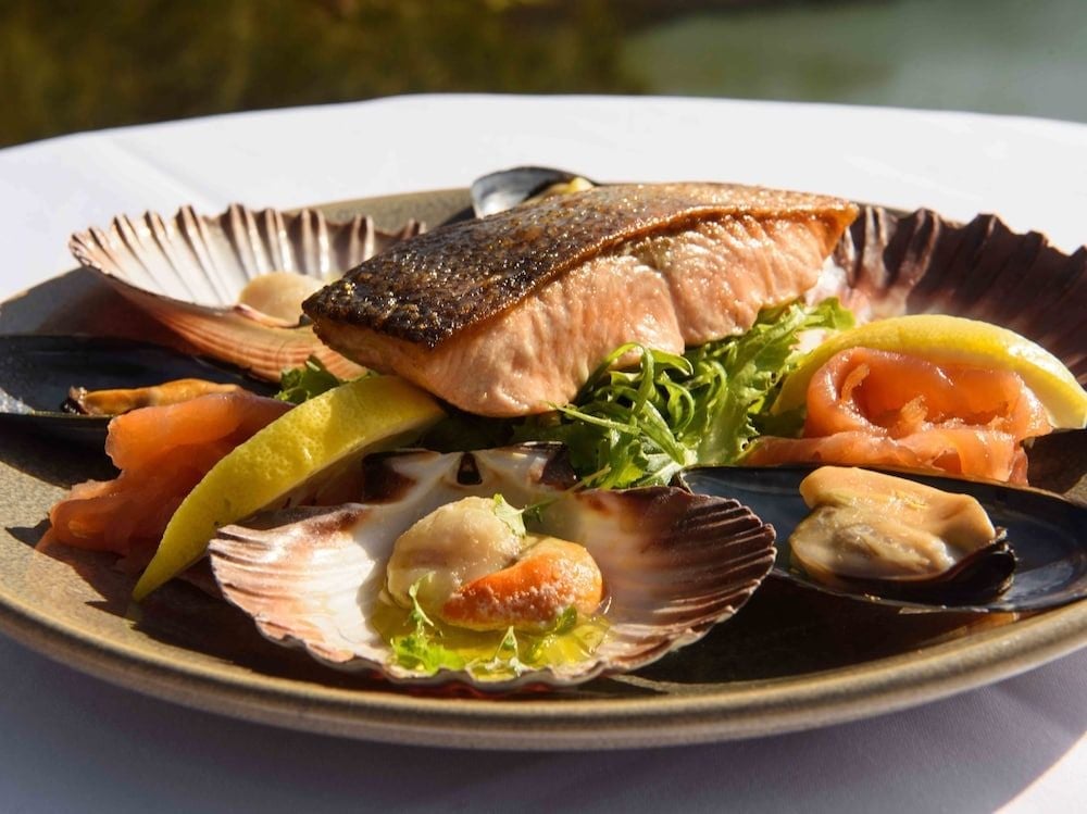 Pan-seared salmon glistens alongside fresh Tasmanian seafood in scallop shells, each plate a celebration of local waters and culinary artistry at this coastal retreat.