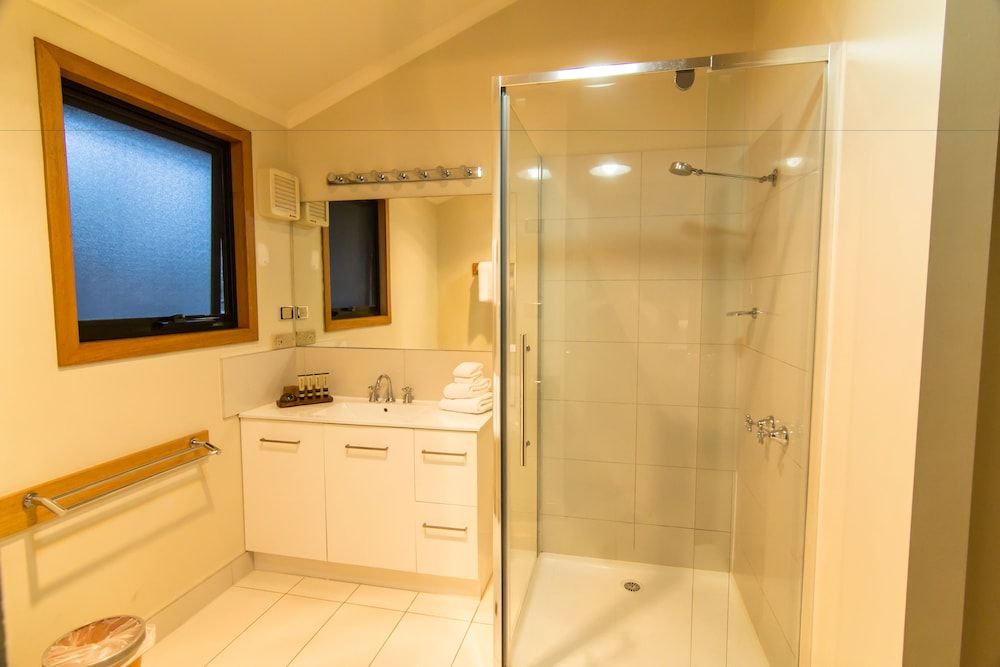 Warm timber accents and frosted glass windows create an intimate spa-like sanctuary, where rainfall showers and pristine white cabinetry invite leisurely morning rituals.