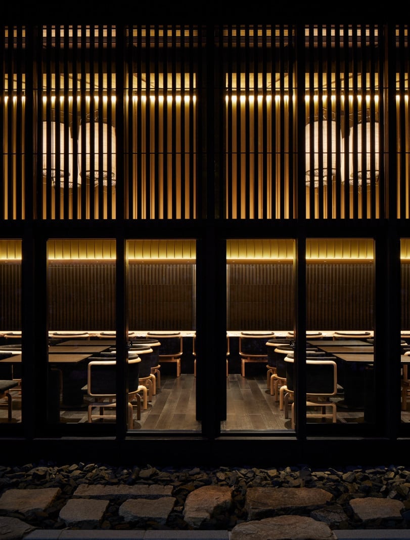 Warm wooden slats and golden light create intimate dining alcoves, where contemporary Japanese design meets the hushed elegance of a traditional ryokan.