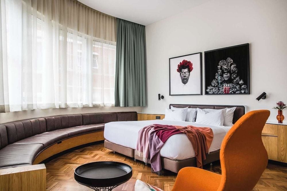 Curved banquette seating and bold contemporary art create an intimate lounge within this sophisticated suite, where warm parquet floors meet modern Australian design sensibilities.