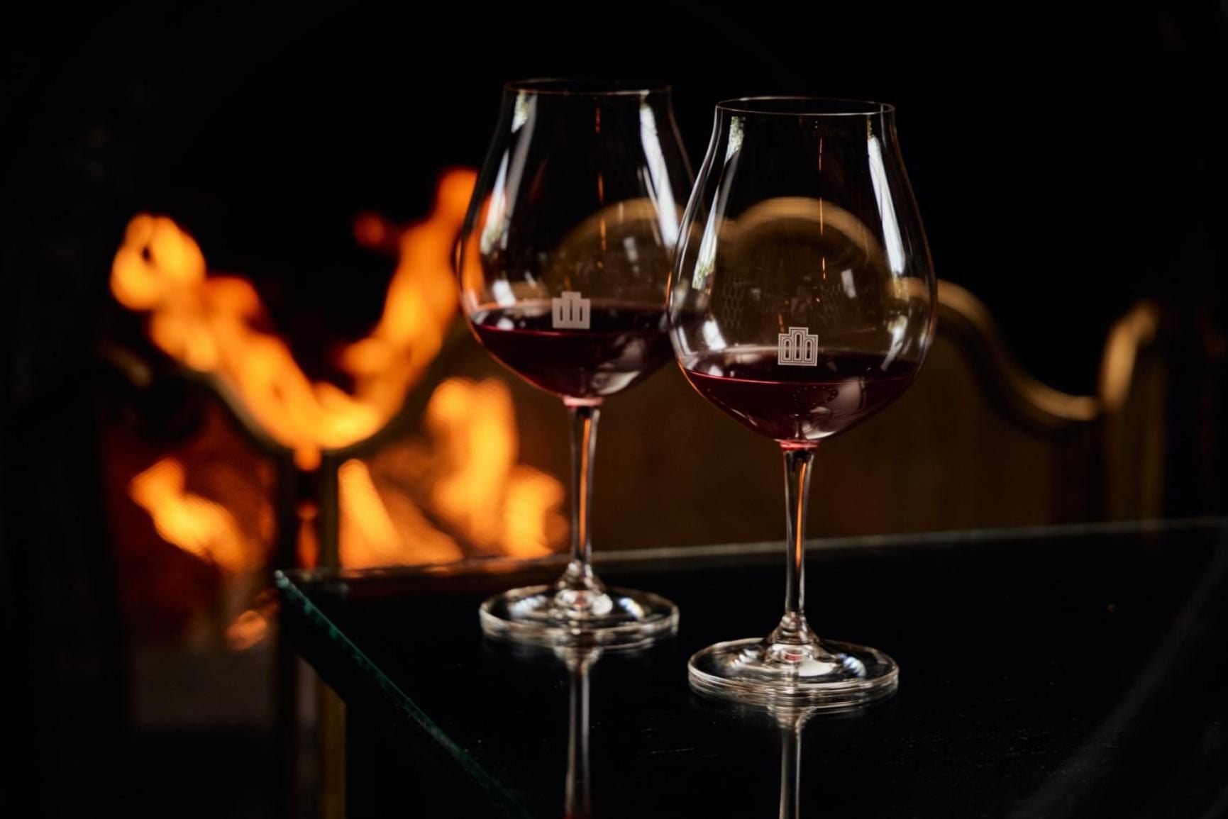 Crystal wine glasses catch firelight's amber glow, creating an intimate setting where Adelaide Hills vintages are savored against the warmth of flickering flames.