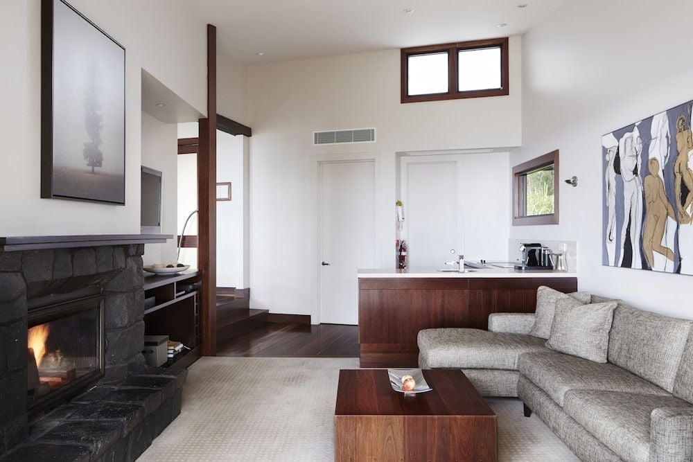 Charcoal stone fireplace anchors this sophisticated suite where walnut cabinetry meets plush sectional seating, creating an intimate mountain retreat above the valley.