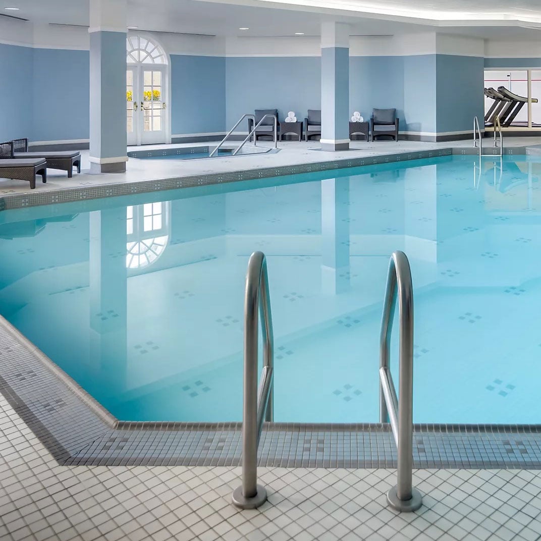 Sunlight streams through arched windows onto crystalline waters where hotel guests find respite in this serene subterranean sanctuary of blue-tiled tranquility.