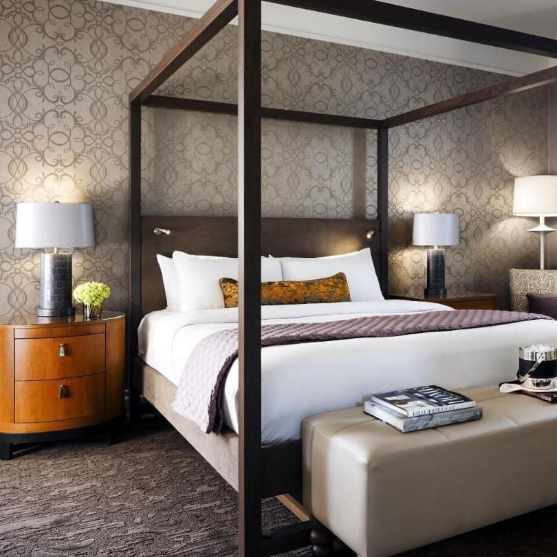 Four-poster drama meets contemporary sophistication in this canopy bed suite, where geometric wallpaper and warm wood nightstands create an intimate urban sanctuary.