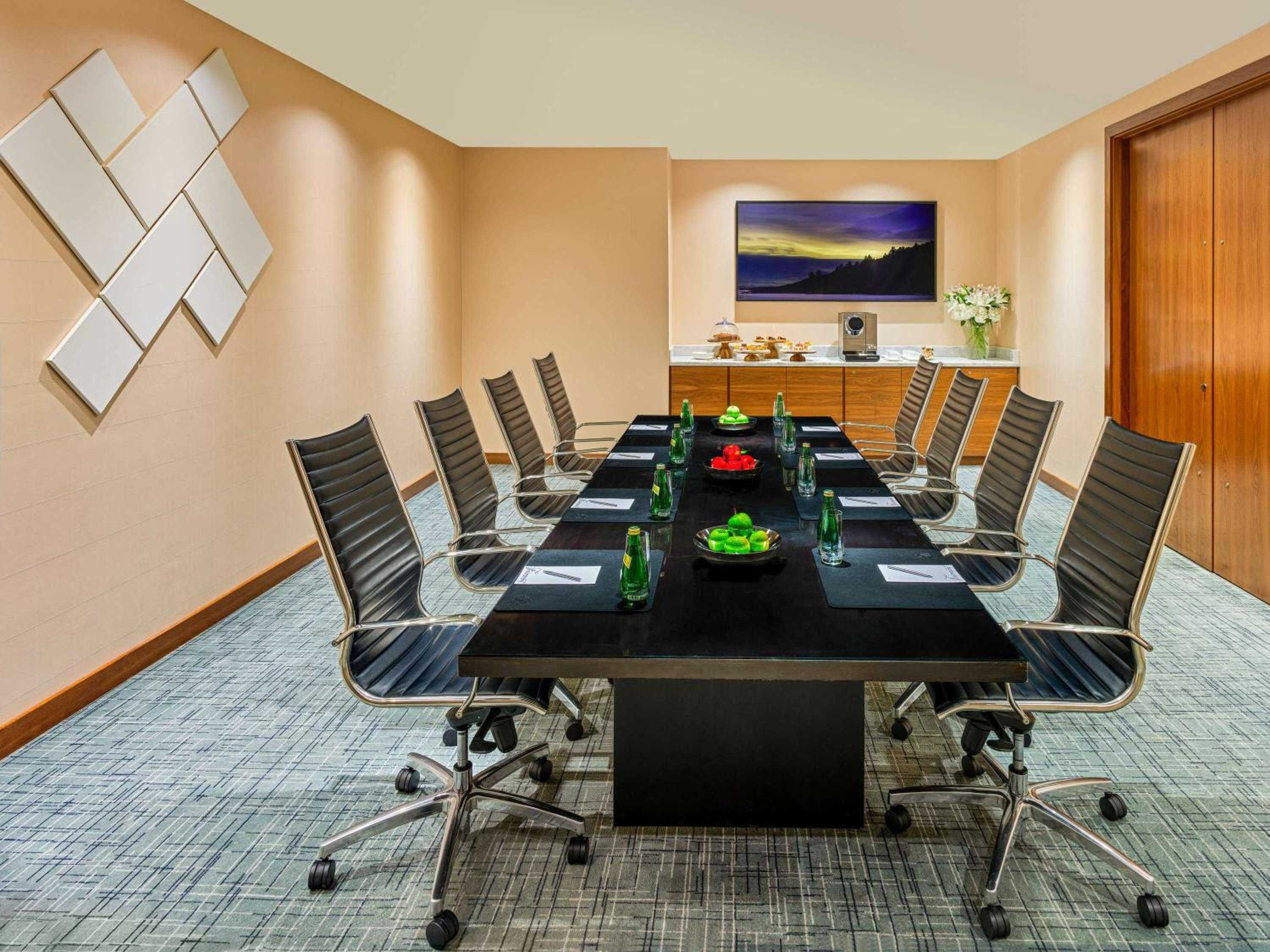 Sleek boardroom sophistication meets warm Pacific Northwest tones, where executive decisions unfold around polished dark wood beneath contemporary geometric art installations.
