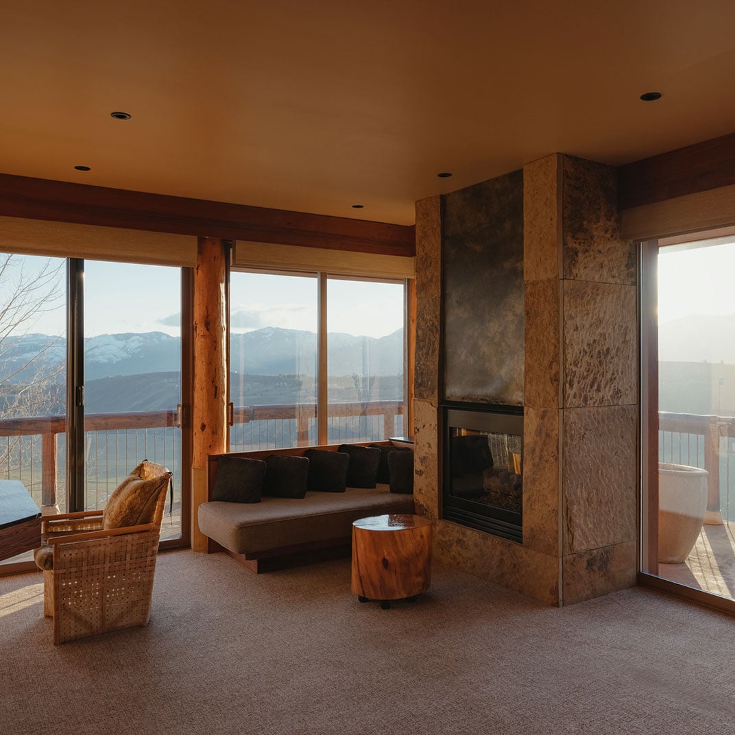 Travertine stone meets timber beams in this mountain suite, where a crackling fireplace warms evenings spent watching the Teton Range fade into twilight.