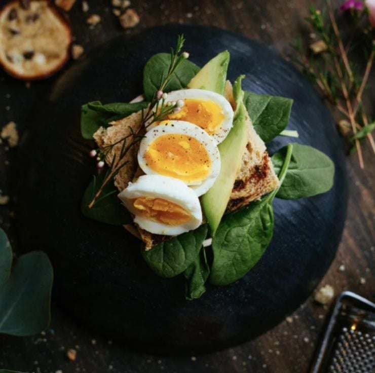 Perfectly soft-boiled eggs crown multigrain toast with fresh spinach and avocado, showcasing the hotel's commitment to elevated comfort food and artful presentation.