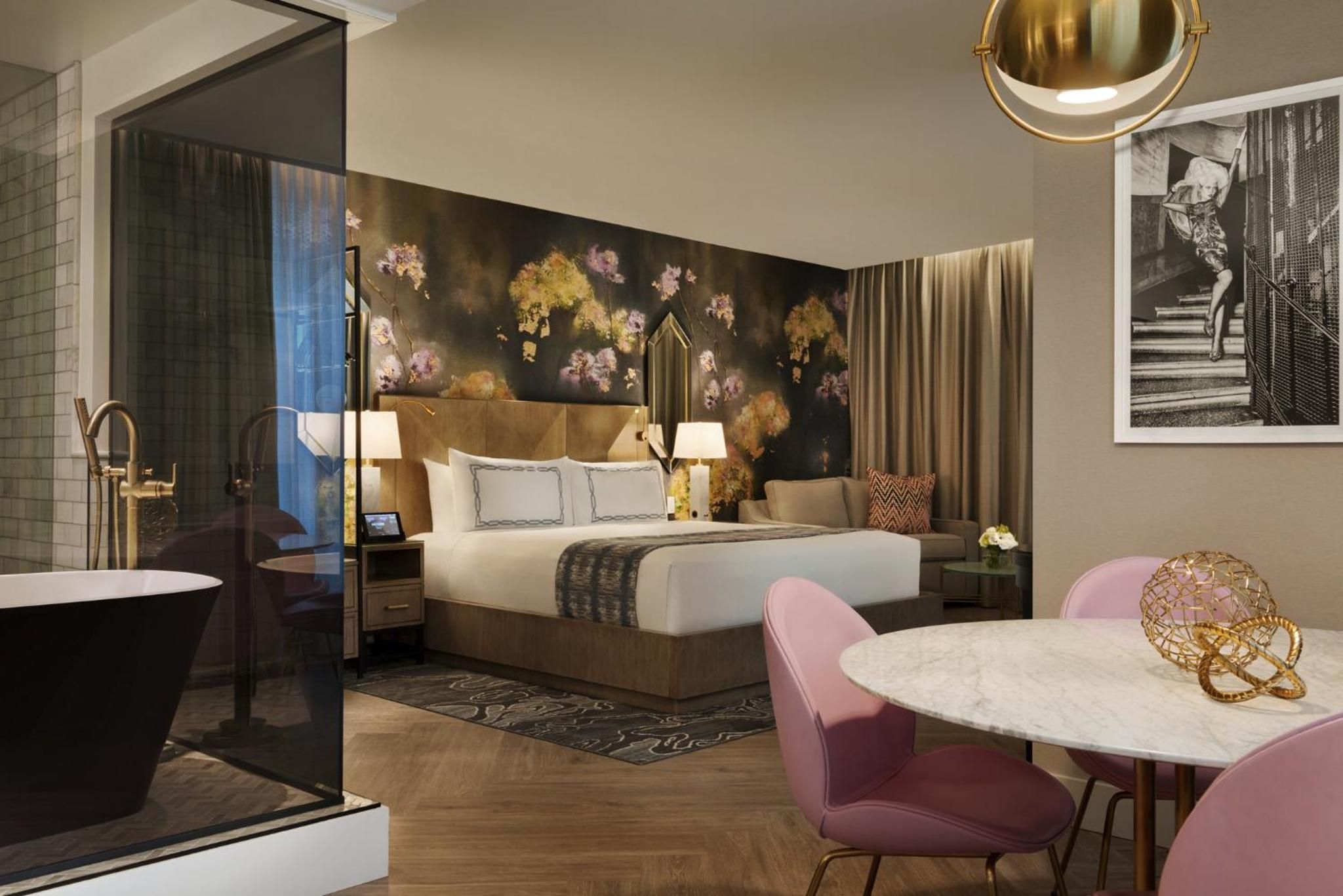Moody floral wallpaper meets rose-gold fixtures in this sophisticated suite, where a freestanding tub beckons beside the plush king bed.