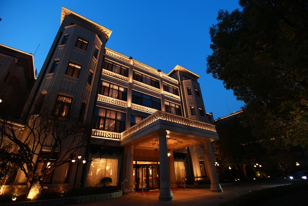 Golden hour bathes the hotel's elegant facade in warm light, where traditional Chinese architectural details meet contemporary luxury in Shanghai's historic French Concession.
