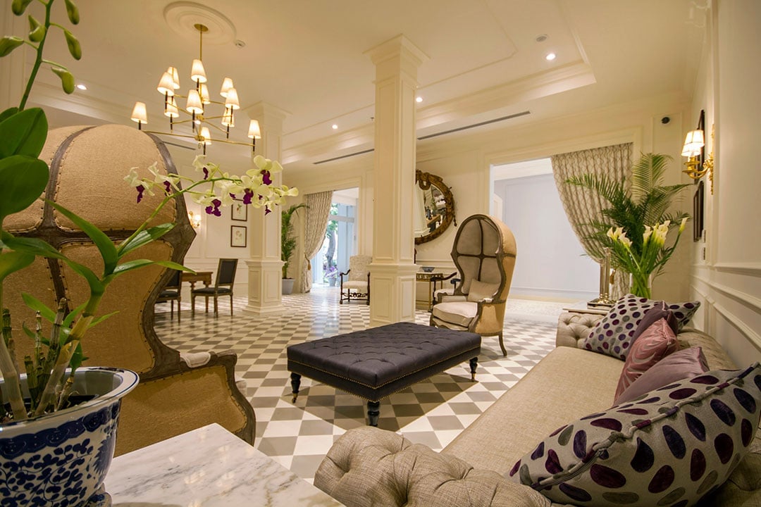 Checkered marble floors gleam beneath soaring ceilings where orchids bloom in ceramic planters, creating an elegant foyer that whispers old-world sophistication.