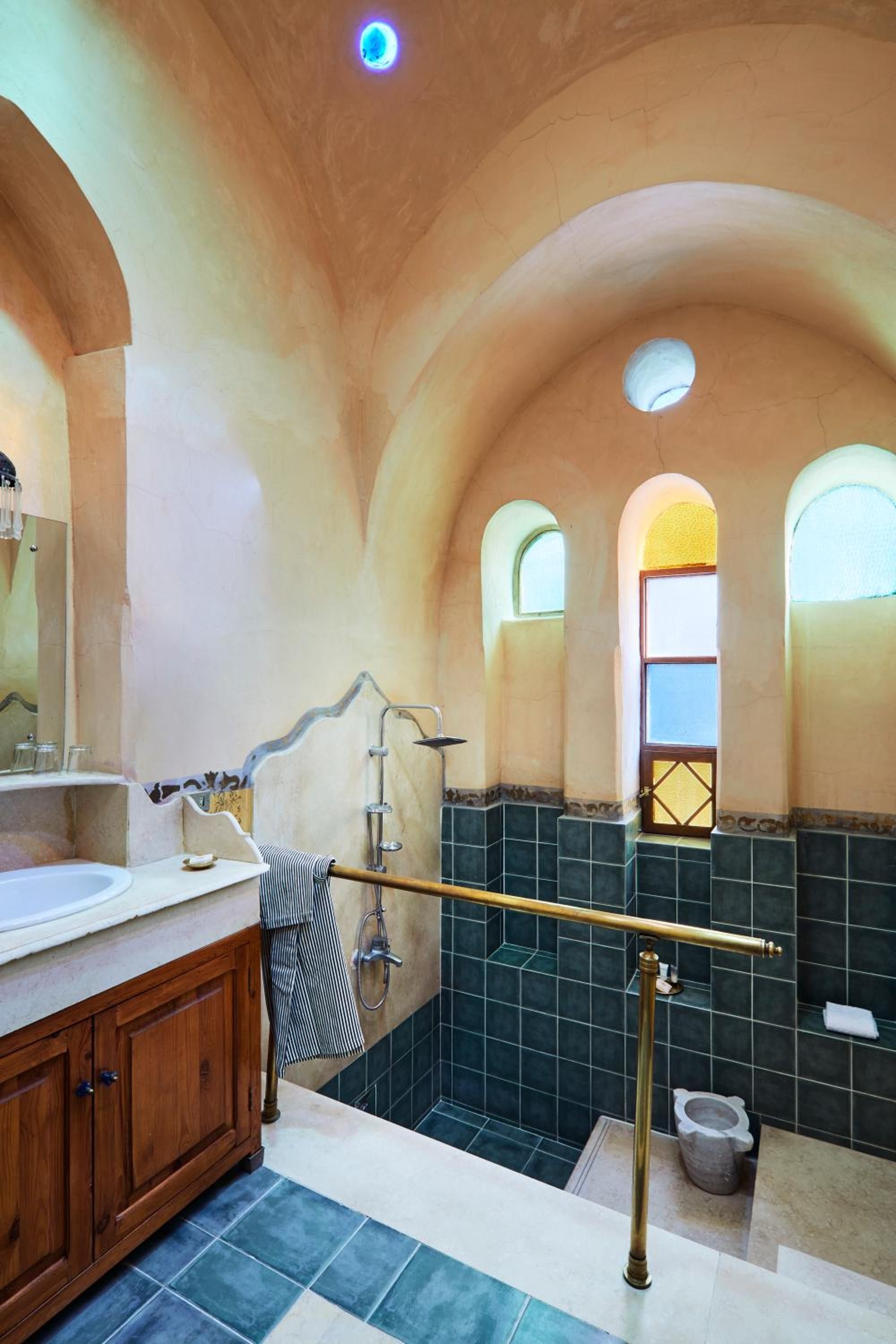 Arched ceilings and jewel-toned tiles create a hammam-inspired sanctuary where brass fixtures and hand-painted details transform daily rituals into luxurious ceremonies.