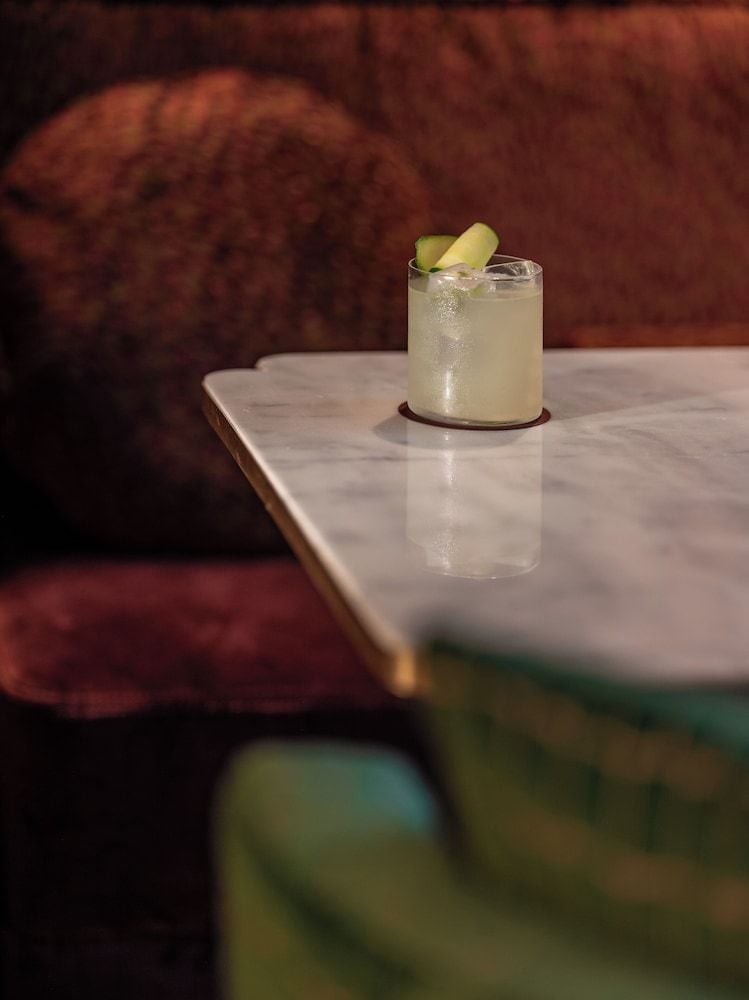 Artisanal cocktails gleam on marble tables beneath warm lamplight, where intimate conversation flows as smoothly as the expertly crafted libations at this sophisticated drinking den.