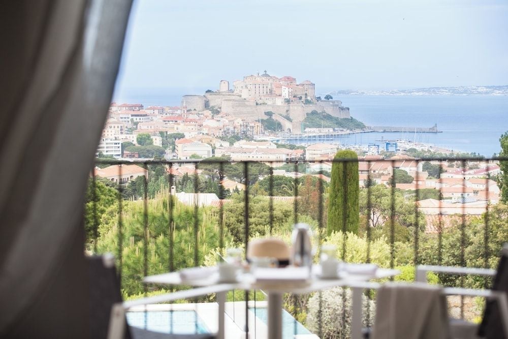 From your private terrace, Calvi's historic citadel commands the Mediterranean horizon while breakfast awaits amid fragrant gardens and terracotta rooftops below.