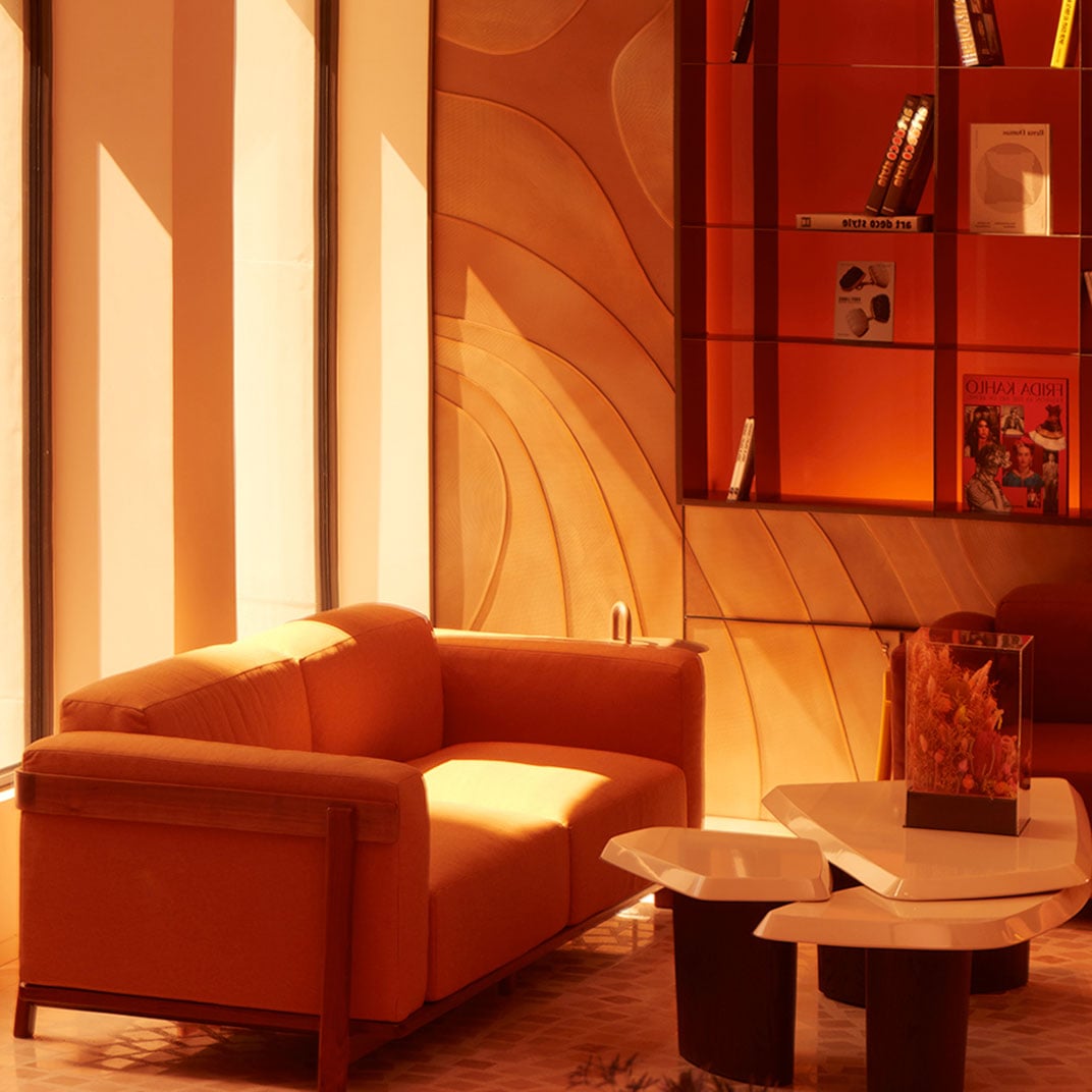 Golden hour light floods the curvaceous reading nook, where burnt orange upholstery and sculptural shelving create an intimate cocoon for afternoon contemplation.