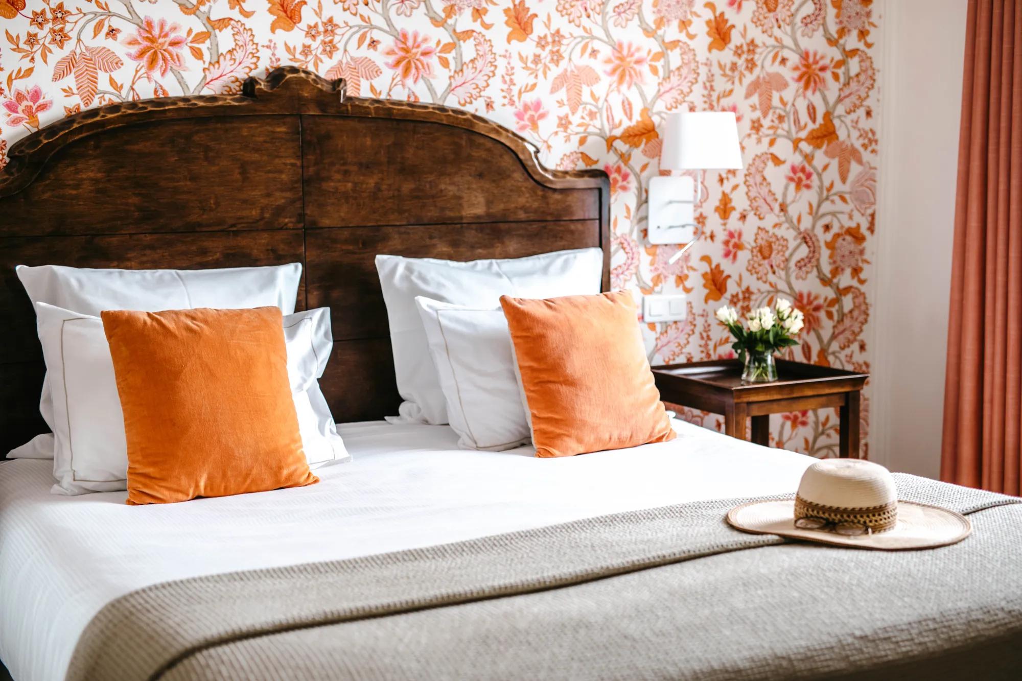 Vibrant orange florals dance across bedroom walls while velvet pillows echo the botanical motif, creating an intimate sanctuary where vintage charm meets contemporary comfort.
