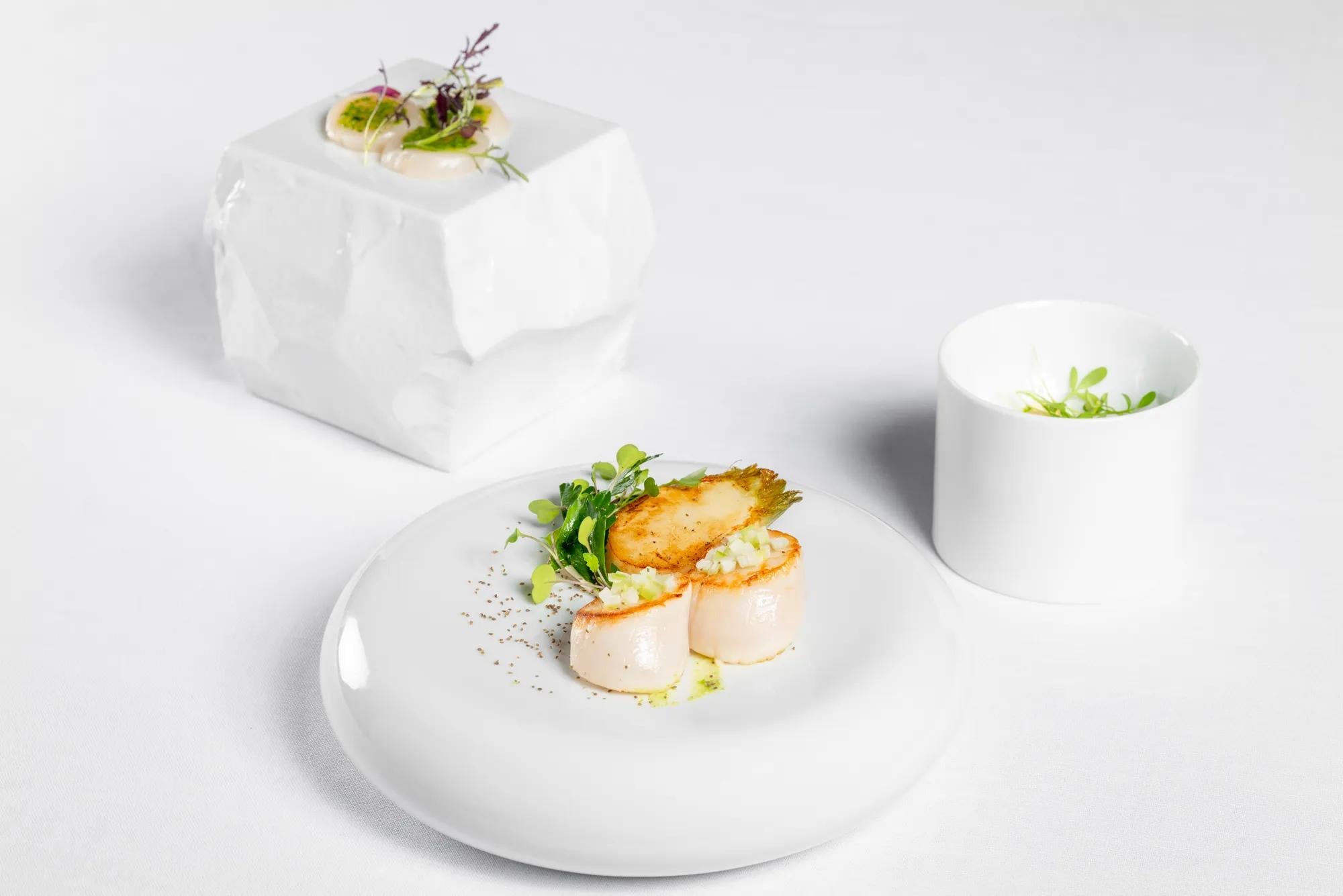 Artfully plated scallops arrive with delicate microgreens and golden tuile, showcasing the culinary precision that defines dining at this refined Chantilly retreat.