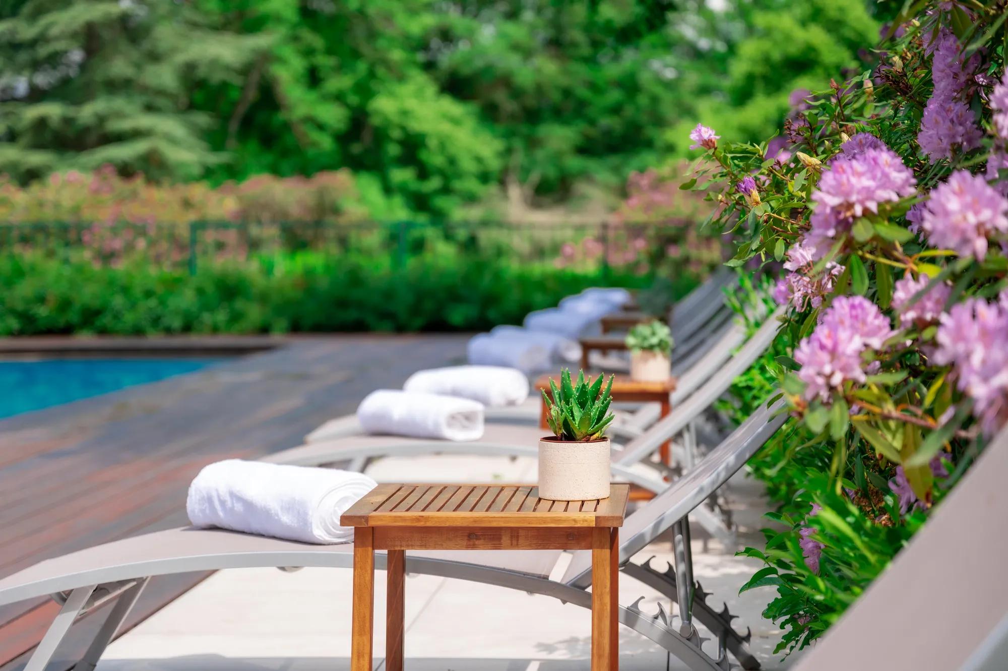 Poolside loungers draped in crisp white linens invite lazy afternoons, while fragrant purple blooms and a potted succulent add intimate touches to this serene retreat.