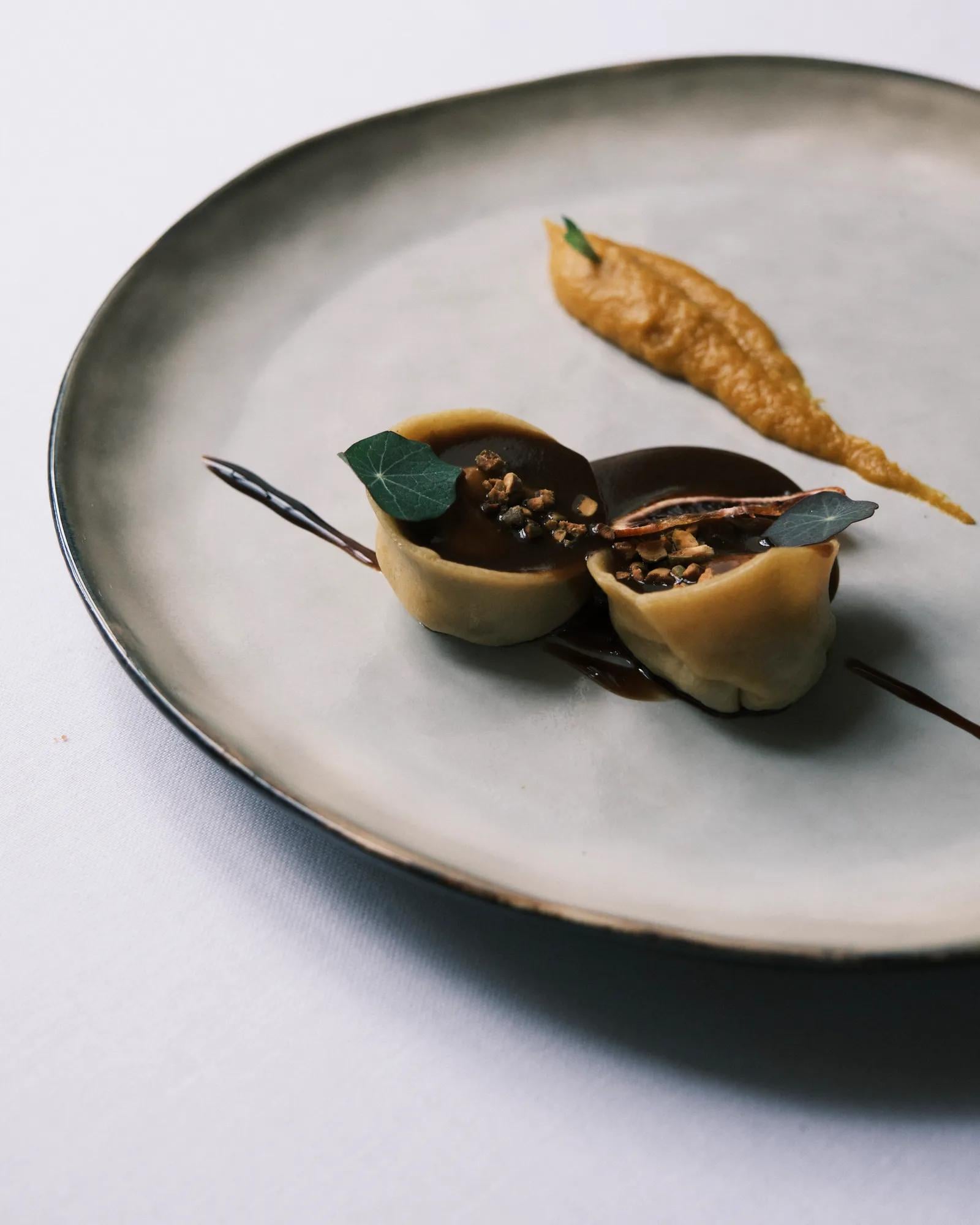 Artfully plated dumplings rest in dark chocolate sauce, their delicate wrappers concealing aromatic spices that perfume this monastery-turned-culinary sanctuary.