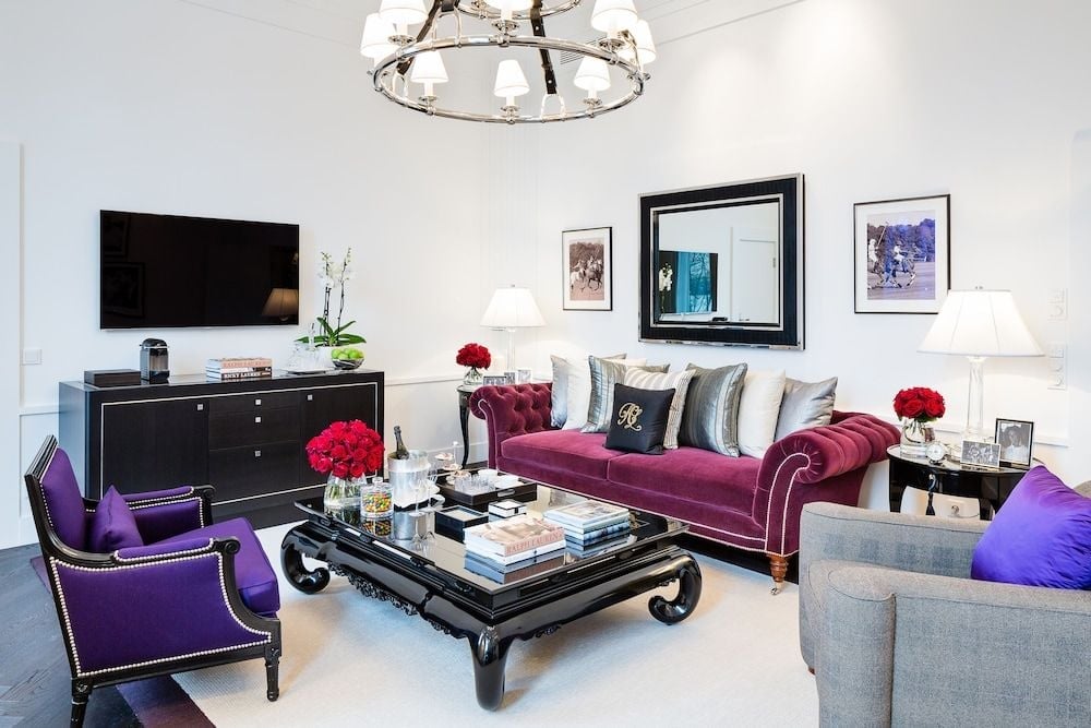 Jewel-toned velvet seating and a dramatic black lacquer coffee table create an opulent living space where contemporary luxury meets classic European elegance.