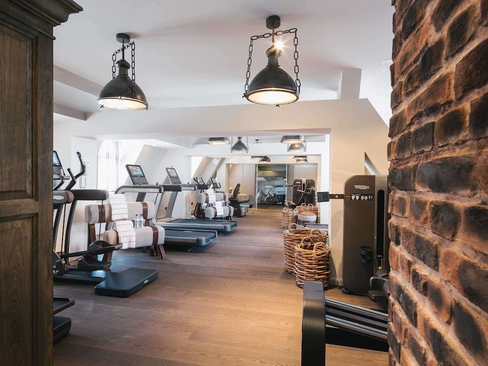 Industrial pendant lights cast warm glows over state-of-the-art cardio equipment, while exposed brick walls blend Hamburg's maritime heritage with contemporary wellness luxury.