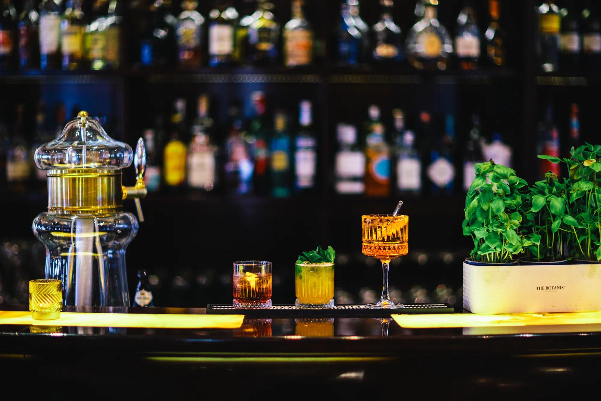Crystal decanters and artfully crafted cocktails showcase the sophisticated drinking culture at this elegant hotel bar, where fresh herbs add aromatic complexity to each handcrafted libation.