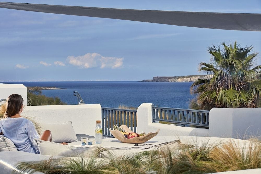 Crisp white terraces frame the sapphire Aegean, where breakfast fruit and morning coffee taste infinitely better against this endless Mediterranean panorama.