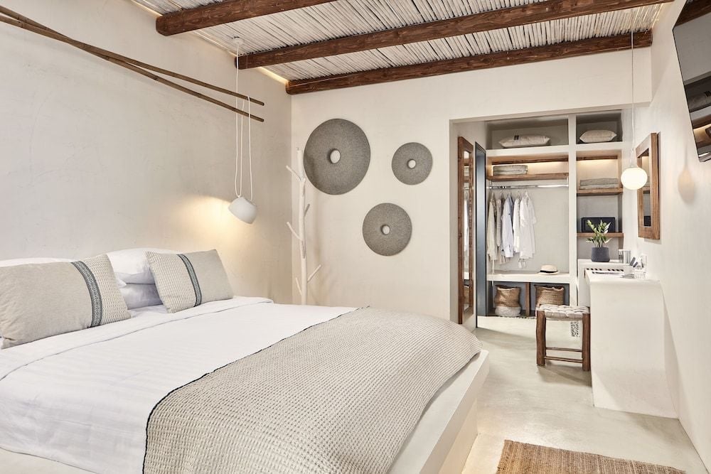 Whitewashed walls and exposed bamboo ceilings create serene Mediterranean charm, while woven pendant lights cast gentle shadows over crisp linens and an inviting walk-in closet.