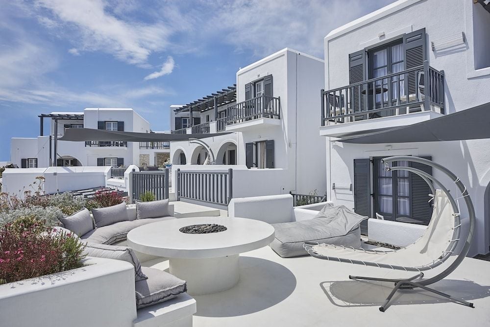 Cycladic minimalism meets modern comfort in the hotel's pristine white terraces, where curved seating and sleek loungers create intimate gathering spaces beneath endless Aegean skies.