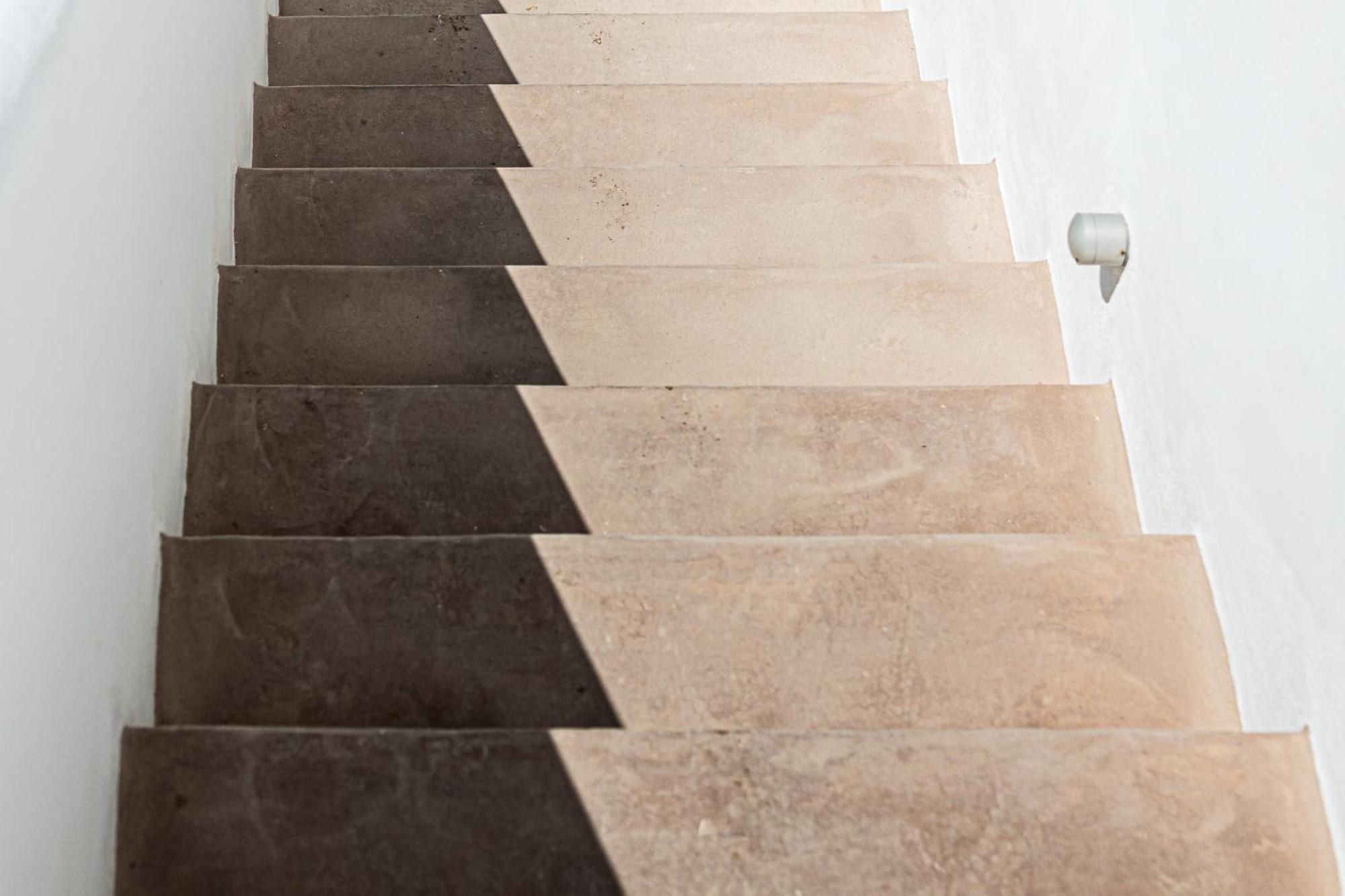 Light plays across travertine steps where shadows create dramatic geometric patterns, showcasing the hotel's sophisticated interplay of natural stone and minimalist design.