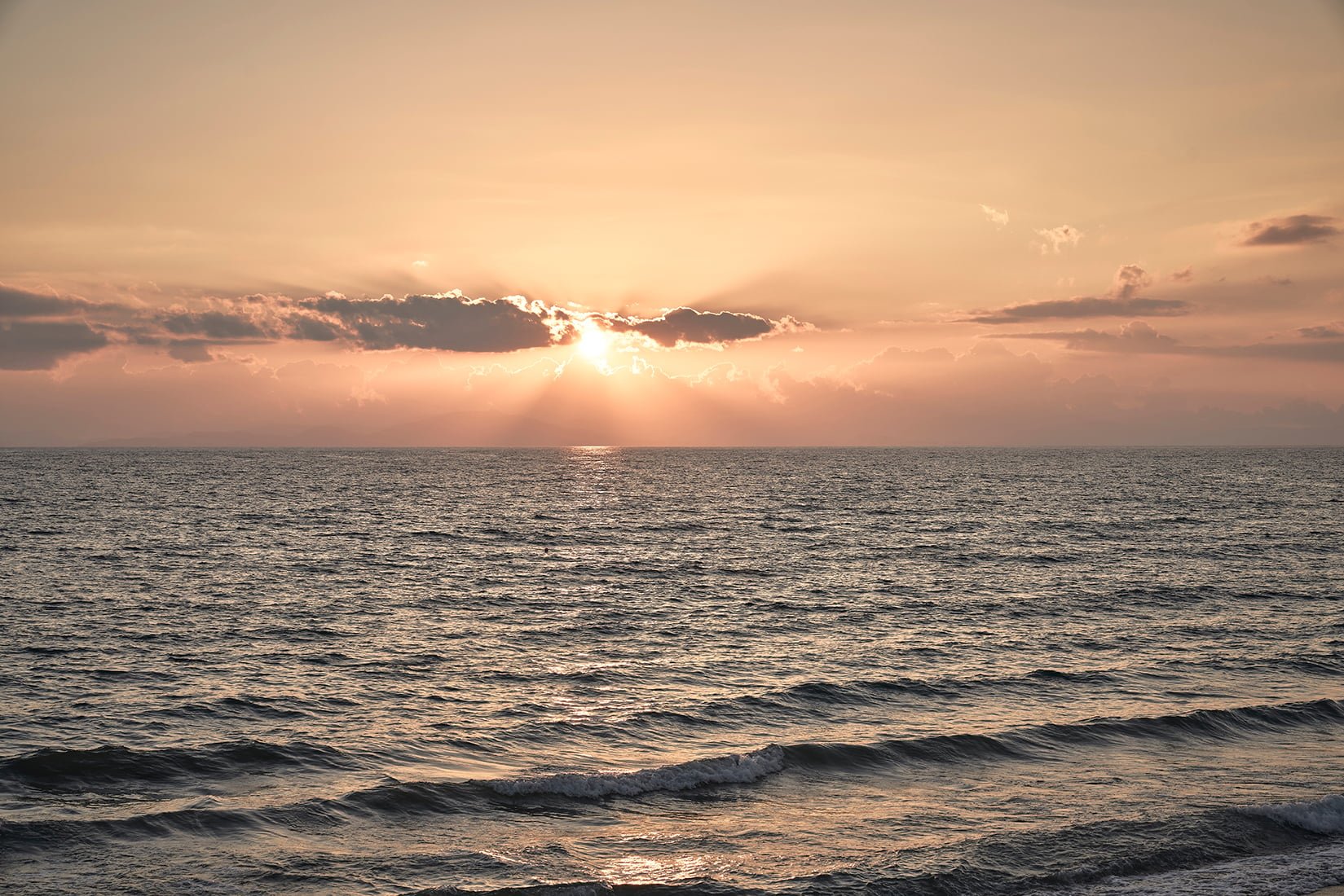 Golden hour paints the Ionian Sea in amber hues as gentle waves roll toward shore, creating the perfect backdrop for sunset contemplation at this coastal retreat.