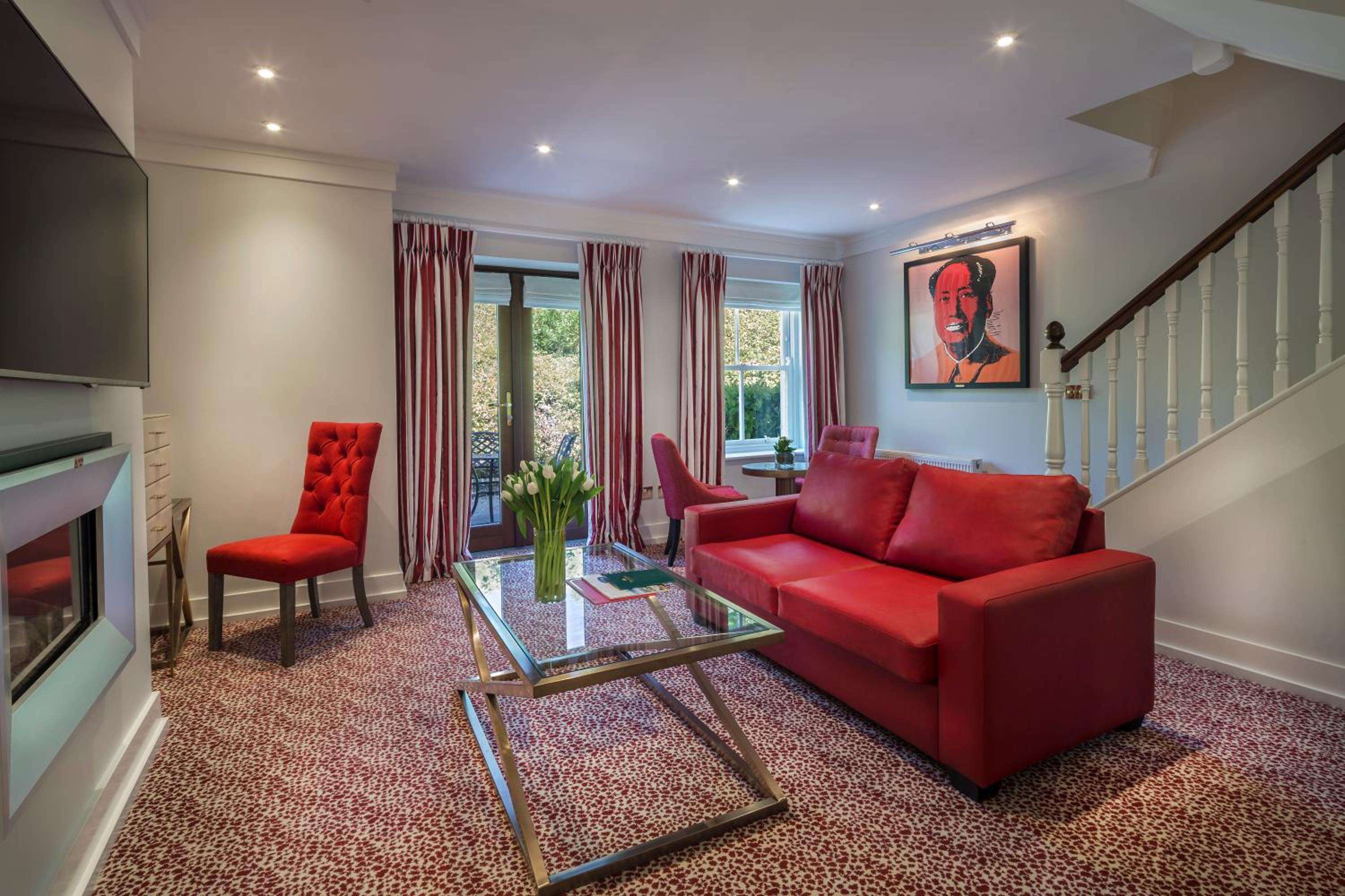 Bold crimson furnishings and contemporary art create drama in this sophisticated living space, where recessed lighting casts a warm glow over polished surfaces and rich textiles.