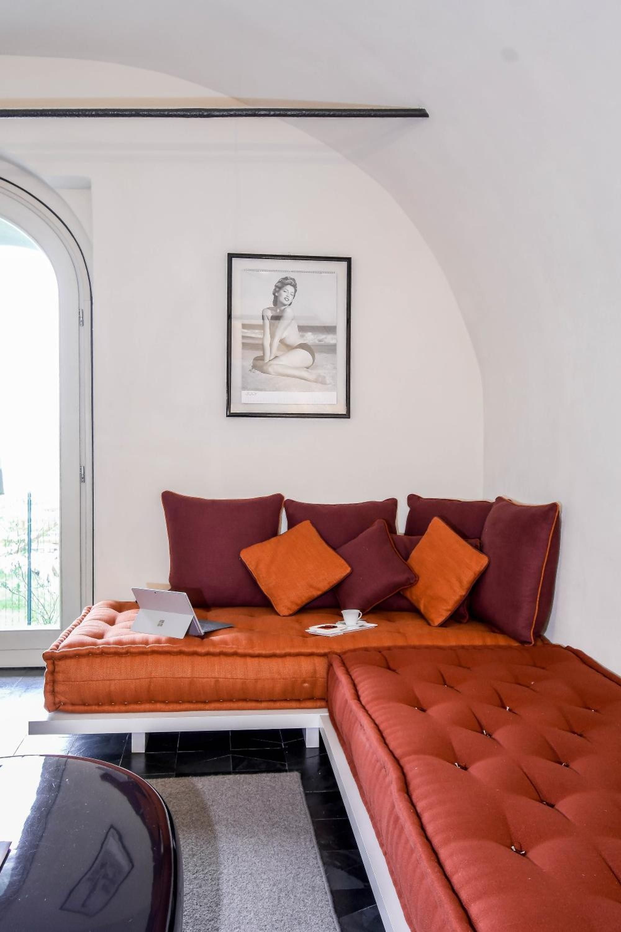 Burnt orange banquettes and wine-colored cushions create a cozy reading nook beneath soaring arched ceilings, where afternoon light streams through oversized windows.
