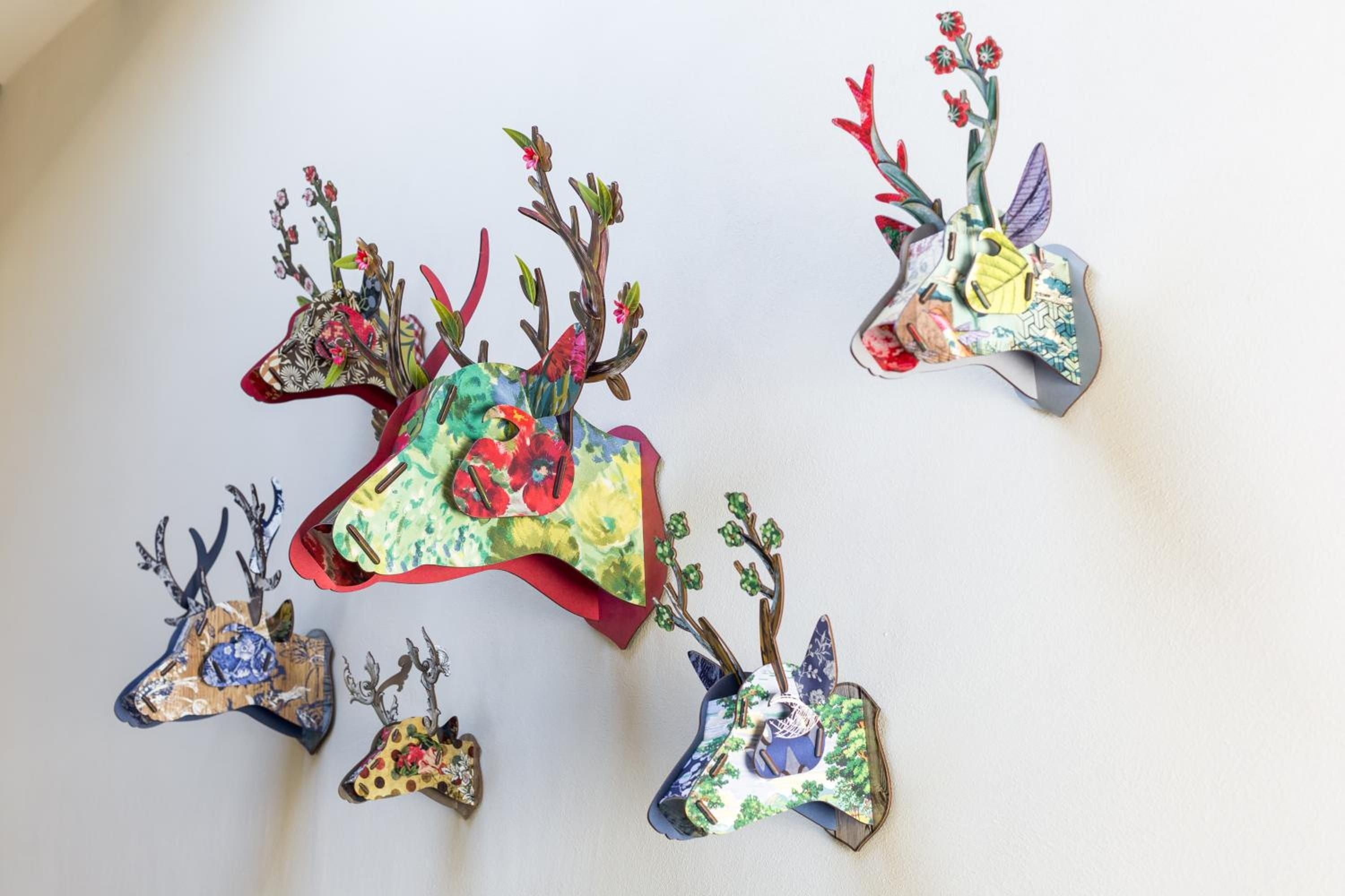 Whimsical paper deer heads adorned with delicate florals and vintage map fragments create an enchanting gallery wall that speaks to the property's artistic soul.