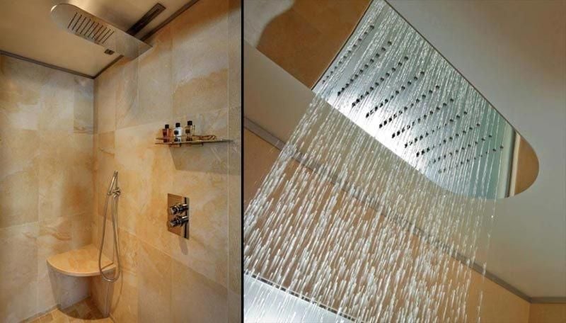 Cascading rainfall showers and honey-toned marble create a sanctuary where ancient monastery walls meet modern indulgence in this luxurious spa-inspired bathroom retreat.