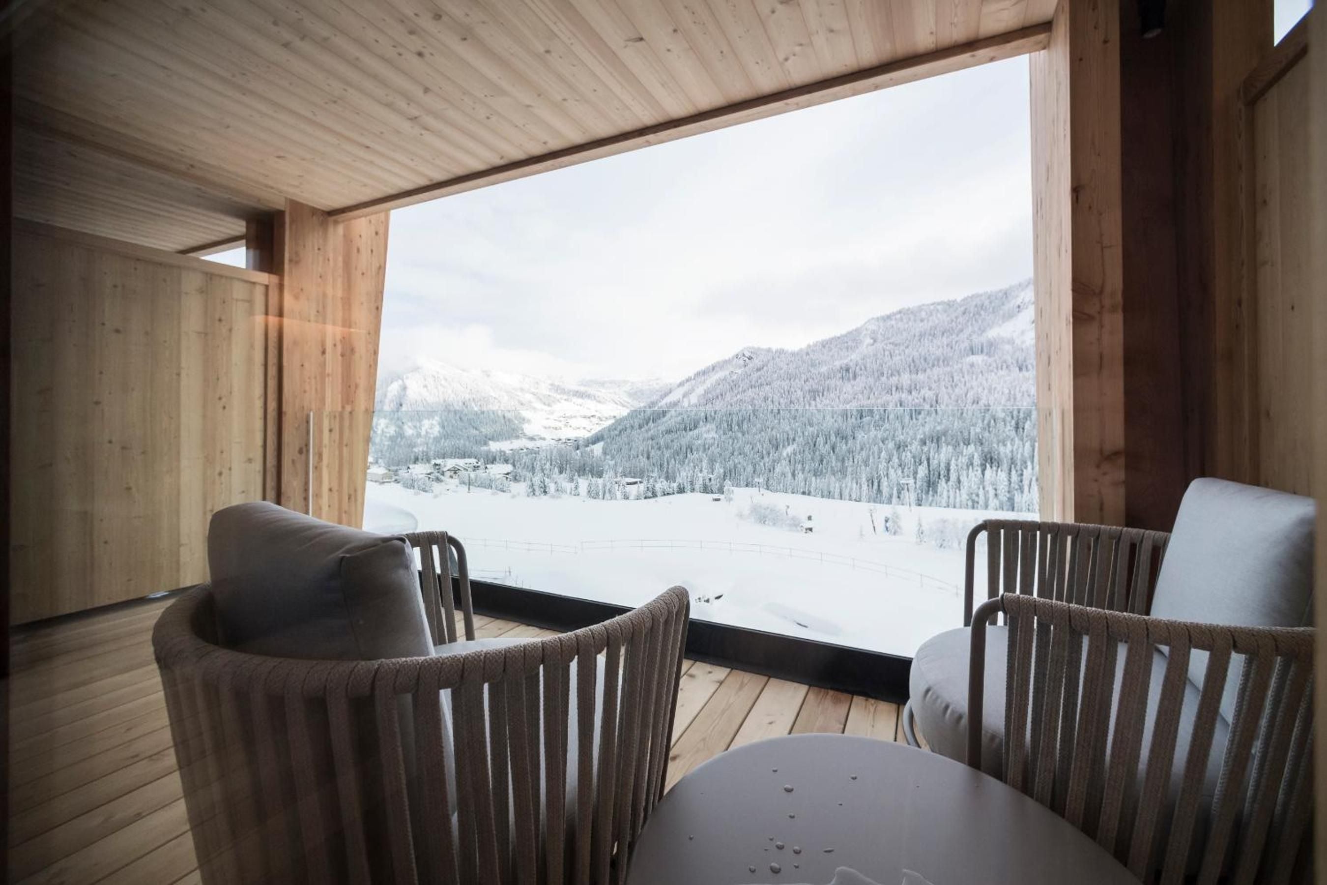 Wrapped in warm timber, this intimate terrace frames snow-dusted Alpine peaks through floor-to-ceiling glass, where modern comfort meets mountain grandeur in perfect stillness.