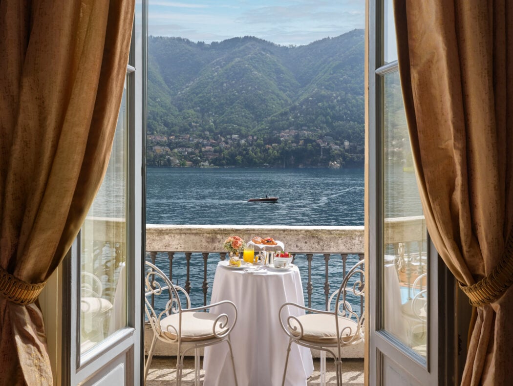 Golden curtains frame a private lakeside terrace where morning coffee overlooks Como's shimmering waters and verdant hillside villas dotting the opposite shore.